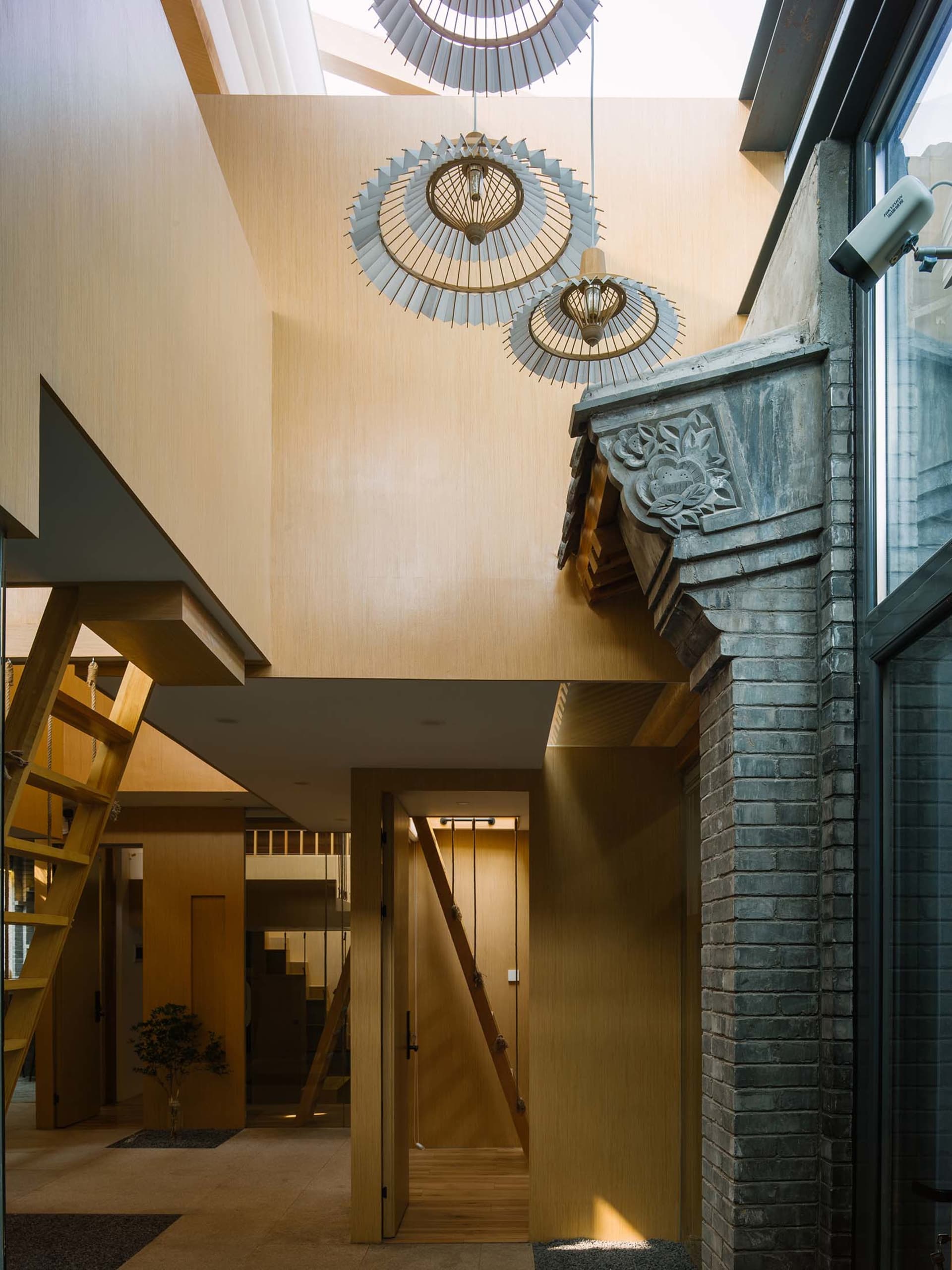 Modern entrance hall with wooden stairs, concrete walls, and wooden lantern chandeliers.