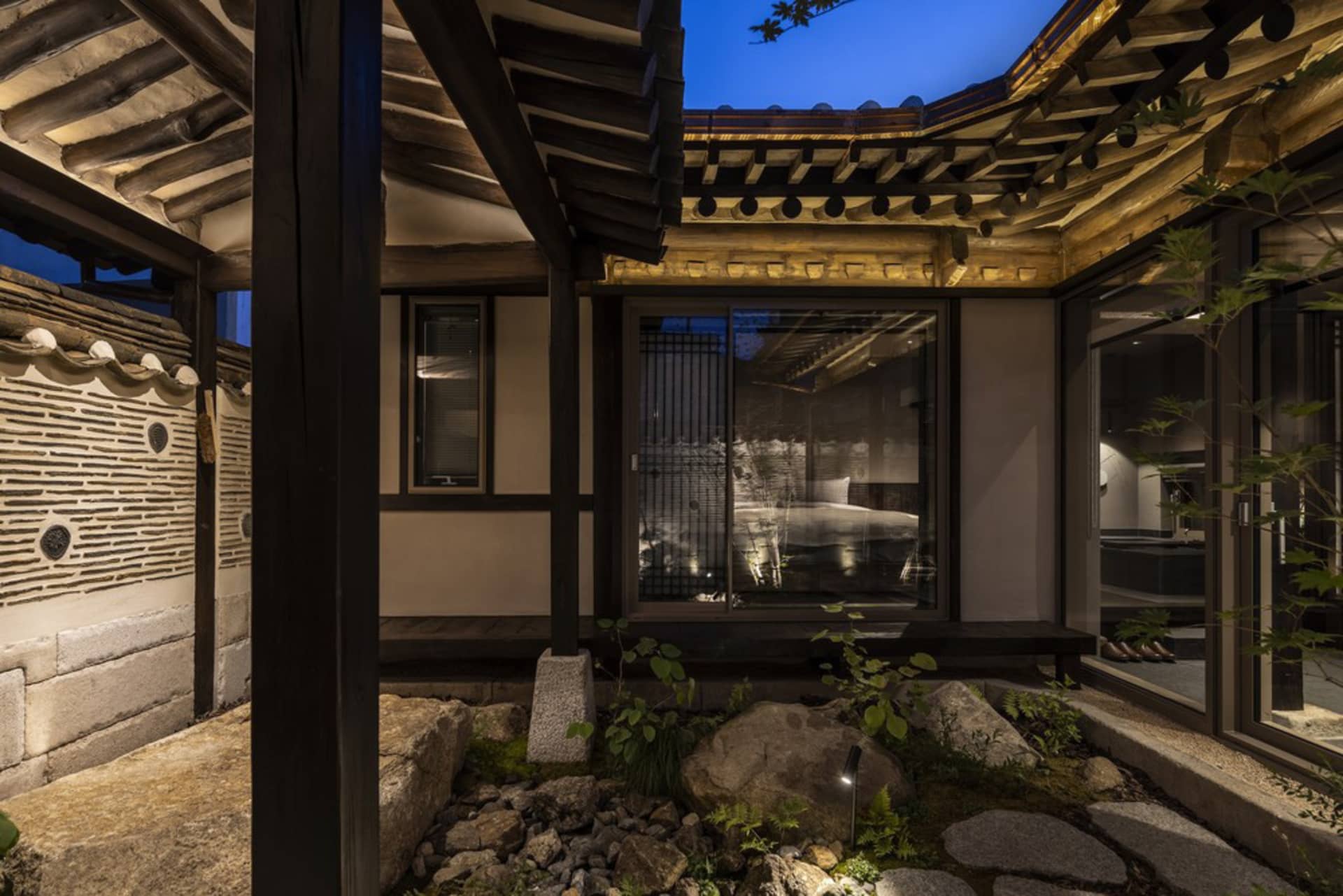 A traditional Korean house with wooden structures and stone pathways at night.