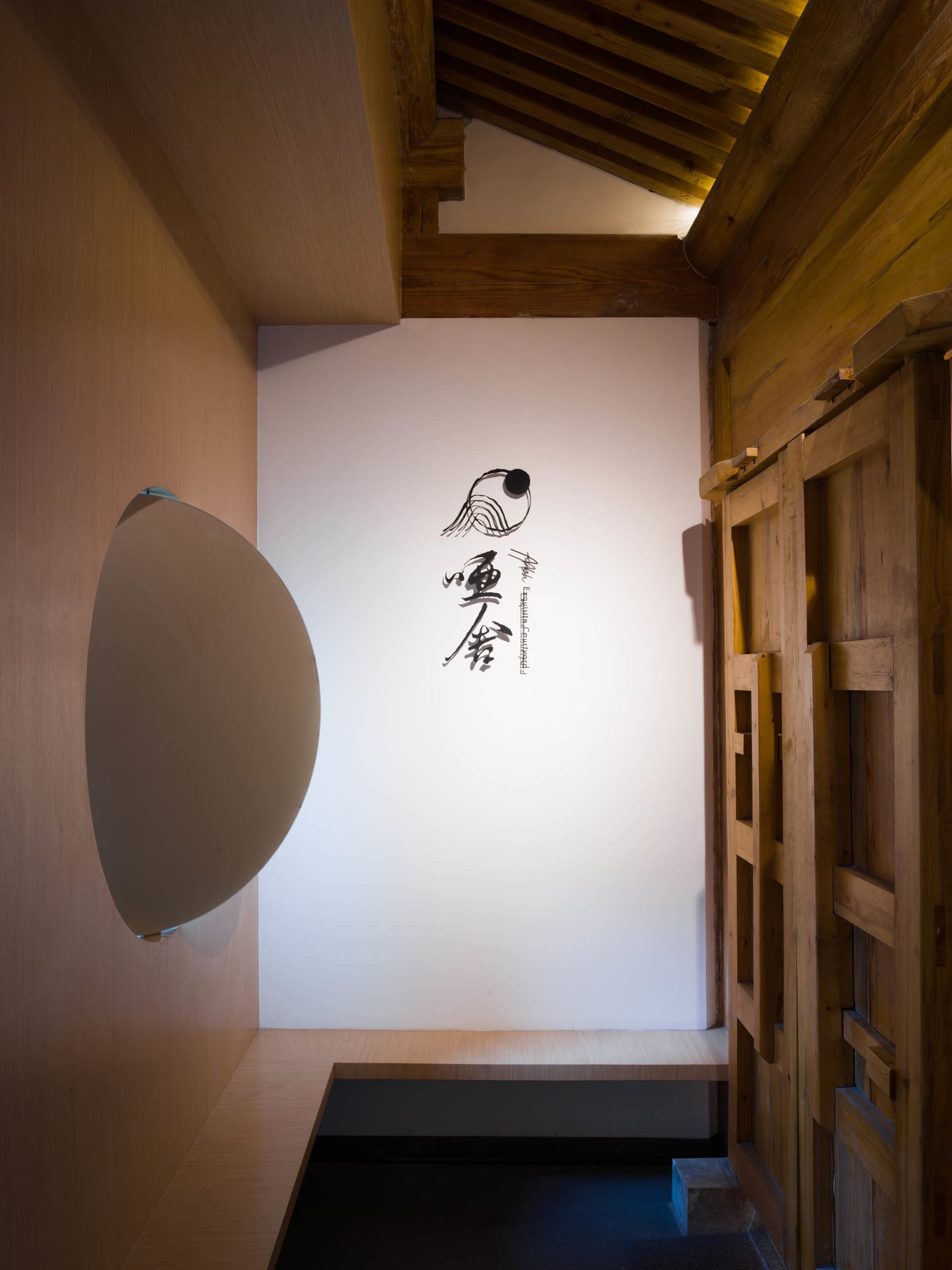 簡約木質室內空間,搭配白色圓形燈具與牆面傳統日式書法。