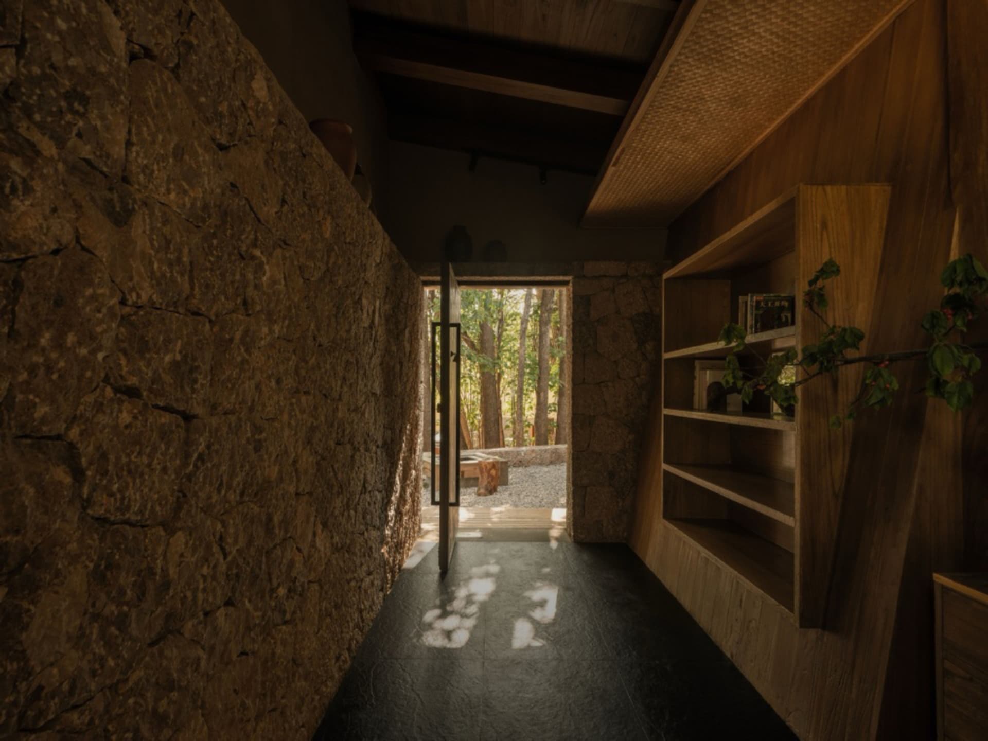 Minimalist interior design featuring stone walls and wooden shelves with greenery.
