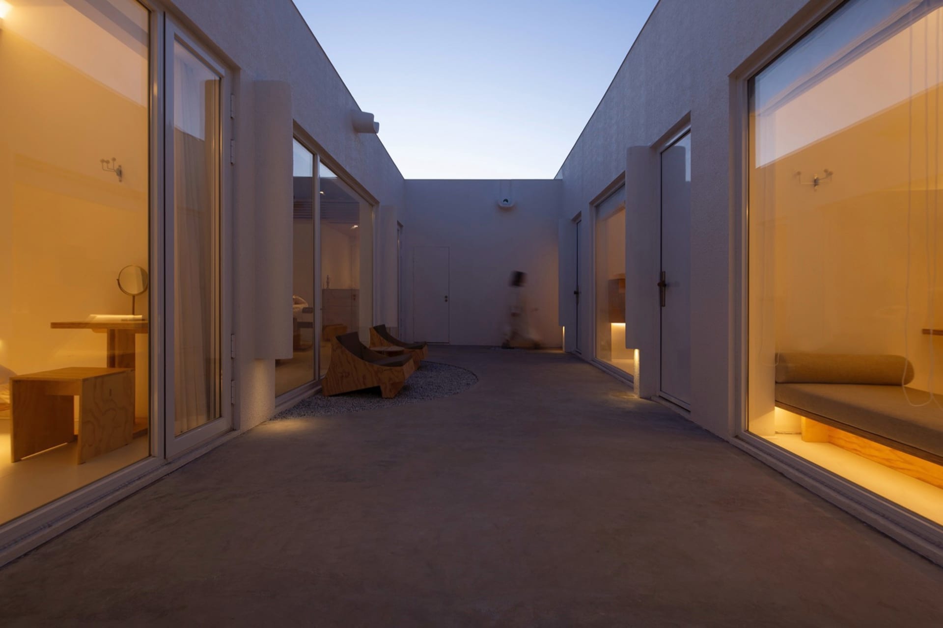 A modern residential interior with a concrete floor, glass walls, and natural light.