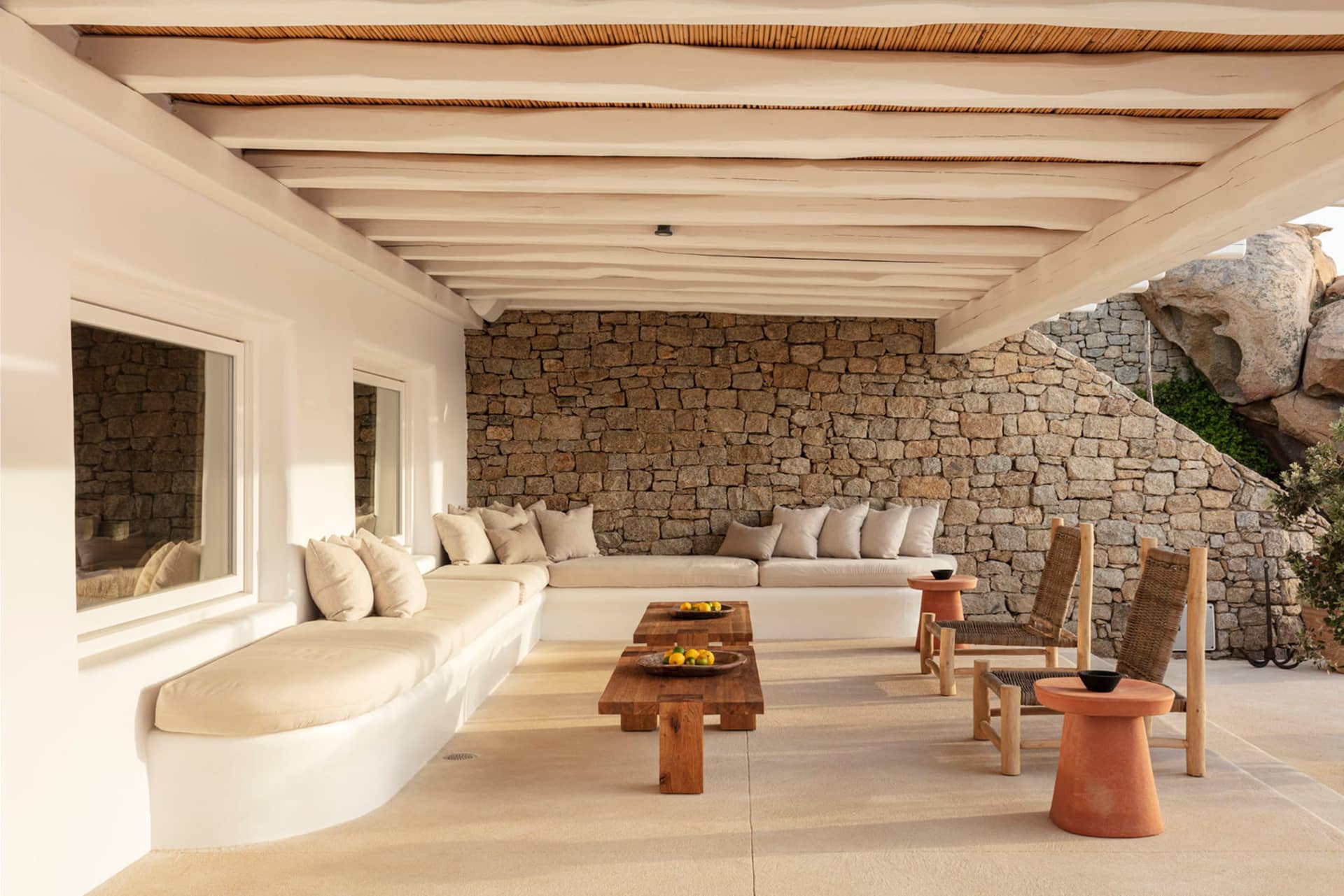 A minimalist residential patio featuring stone walls and comfortable seating areas.
