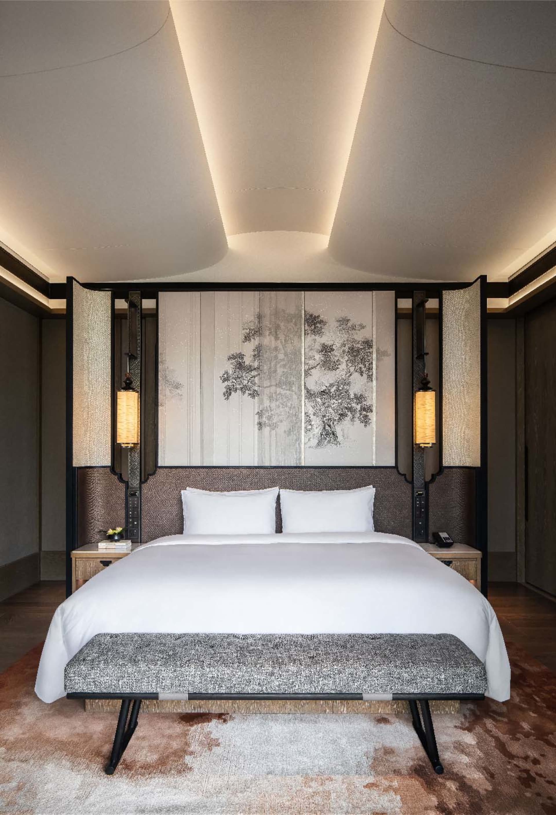 A modern bedroom featuring a textured wooden bed frame and headboard, with minimalist bedding and a bench at the foot of the