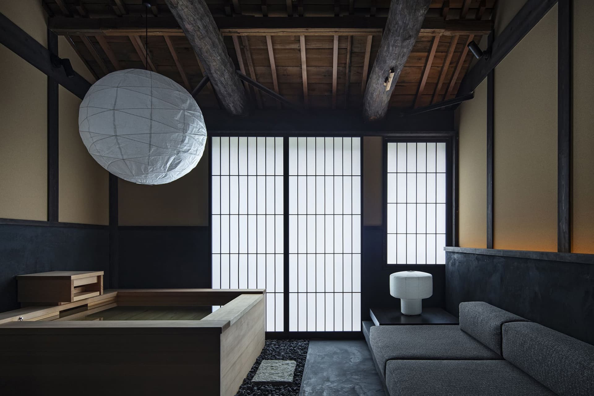 A modern living room with a minimalist and wabi-sabi aesthetic, featuring wood and concrete materials and a large lantern pen