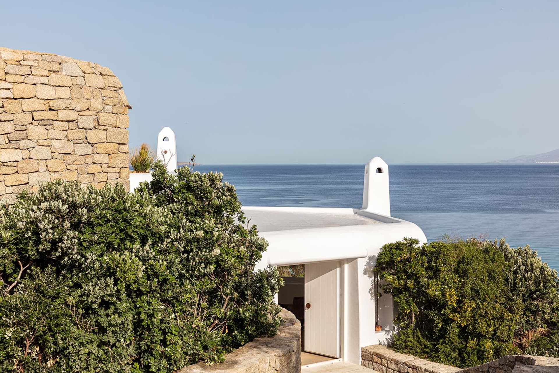 Vacation home with stone and concrete exterior and white accents overlooking the sea.
