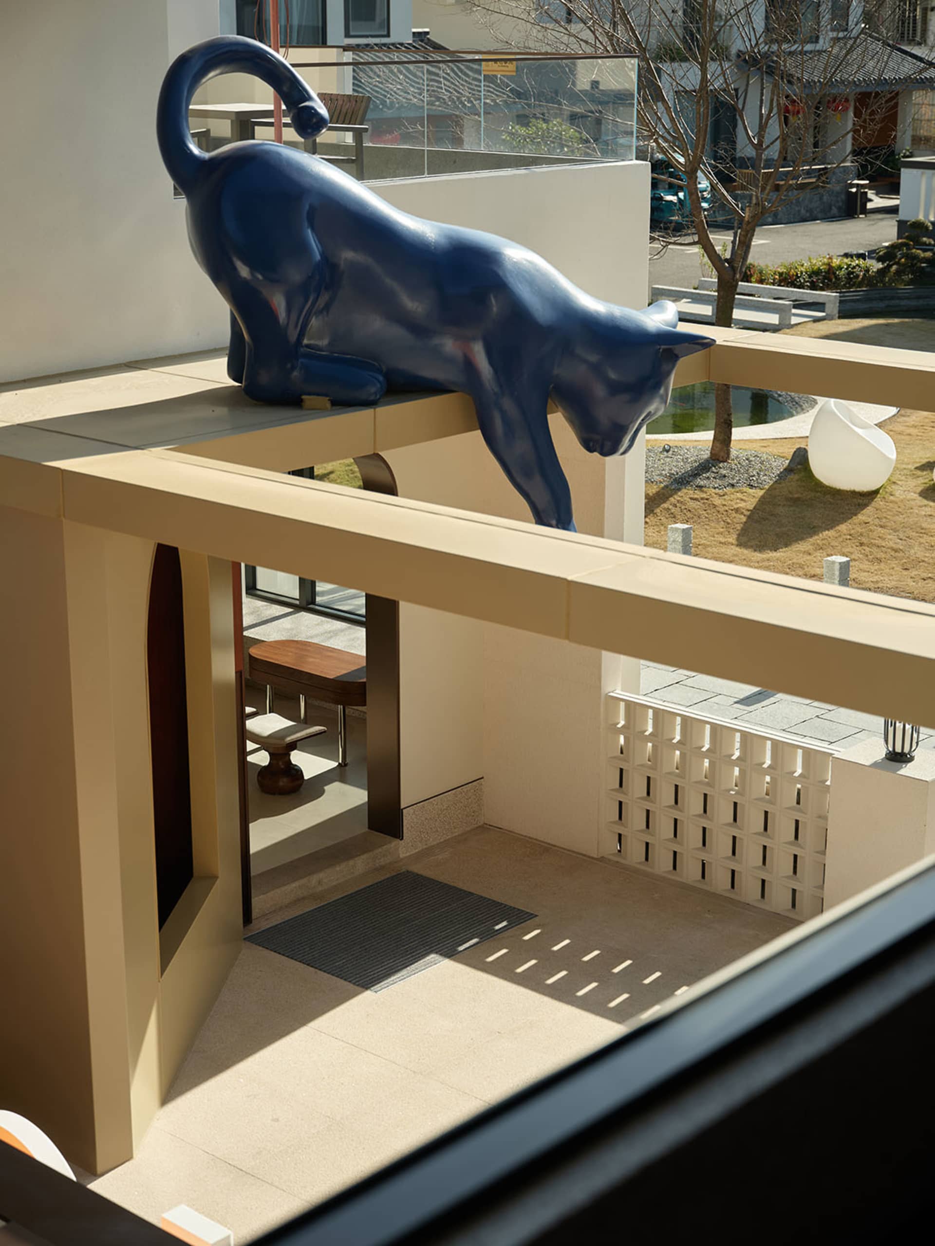 Blue cat sculpture on a concrete balcony interior.