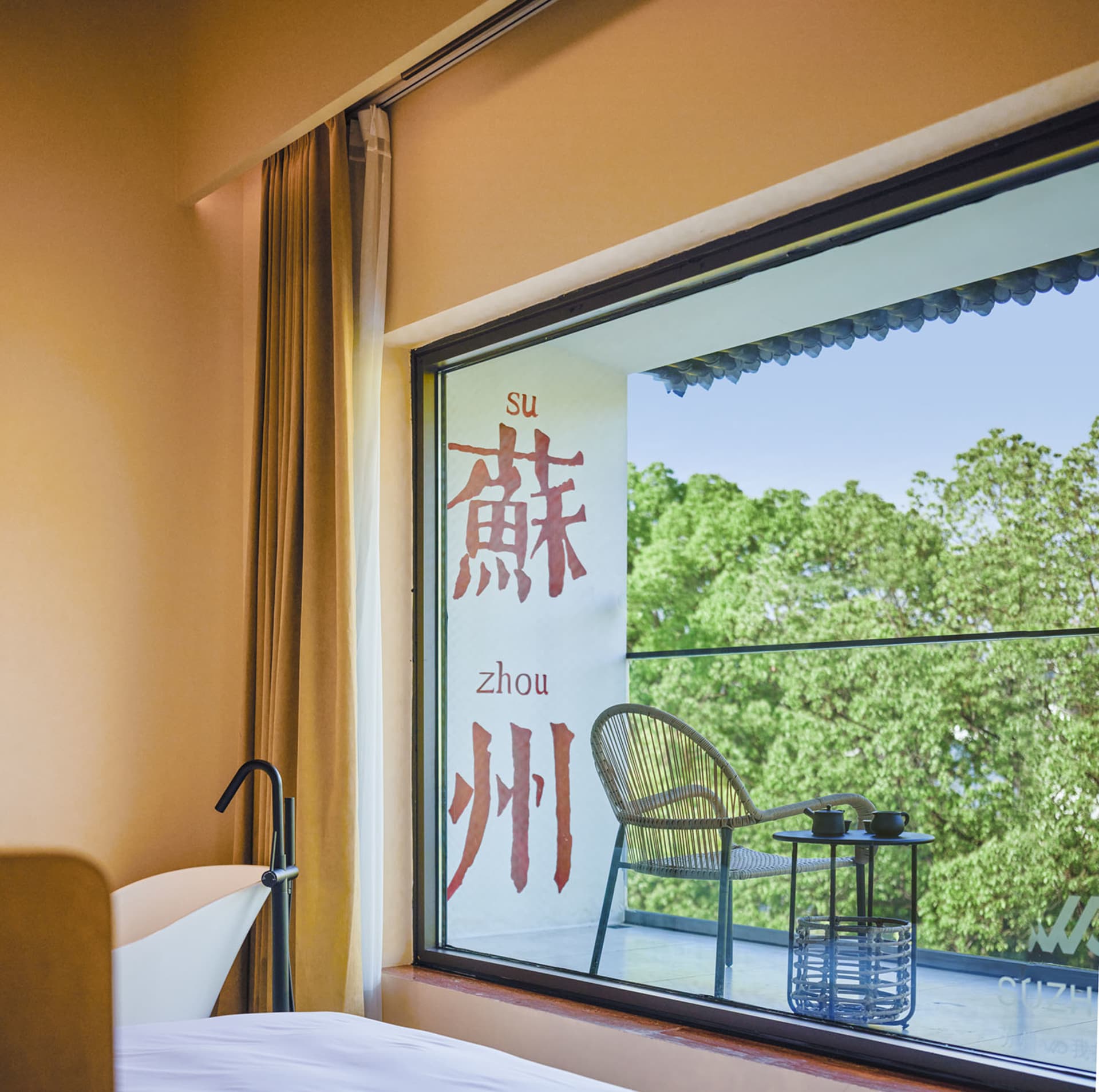 A modern hotel room featuring a glass window overlooking green trees.