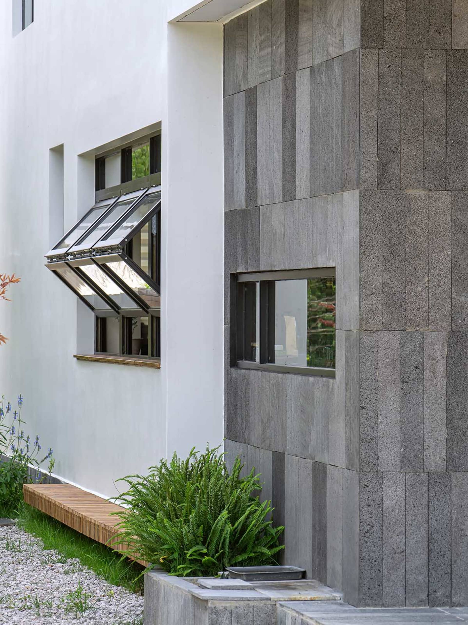 Modern house exterior featuring concrete walls, glass windows, and a wooden window box with plants.