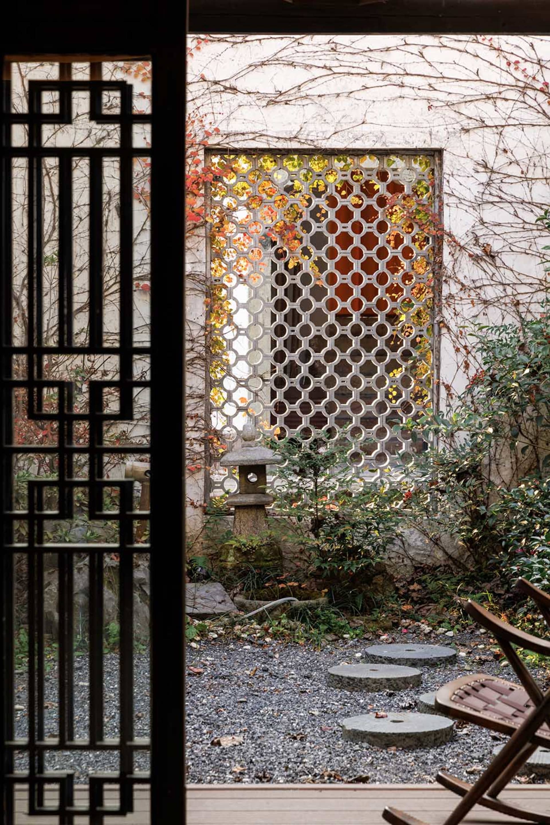 A serene garden scene featuring stone lanterns and wooden fencing, surrounded by wooden floors and stone pathways, with a ble