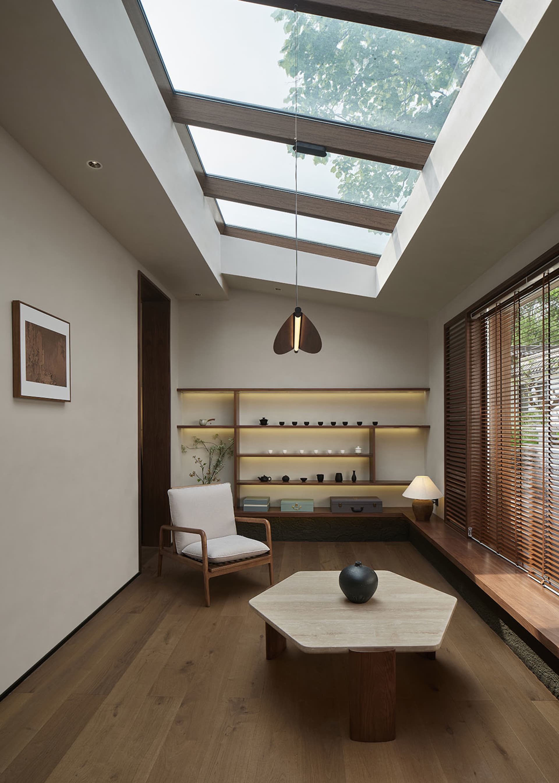 A modern living room with a large skylight, wood flooring, and a hexagonal coffee table.