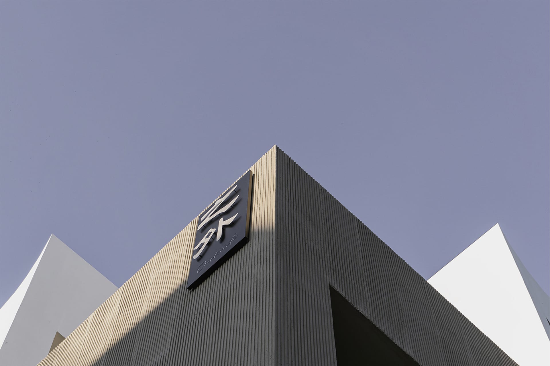 Modern building exterior made of concrete with angular geometric shapes.