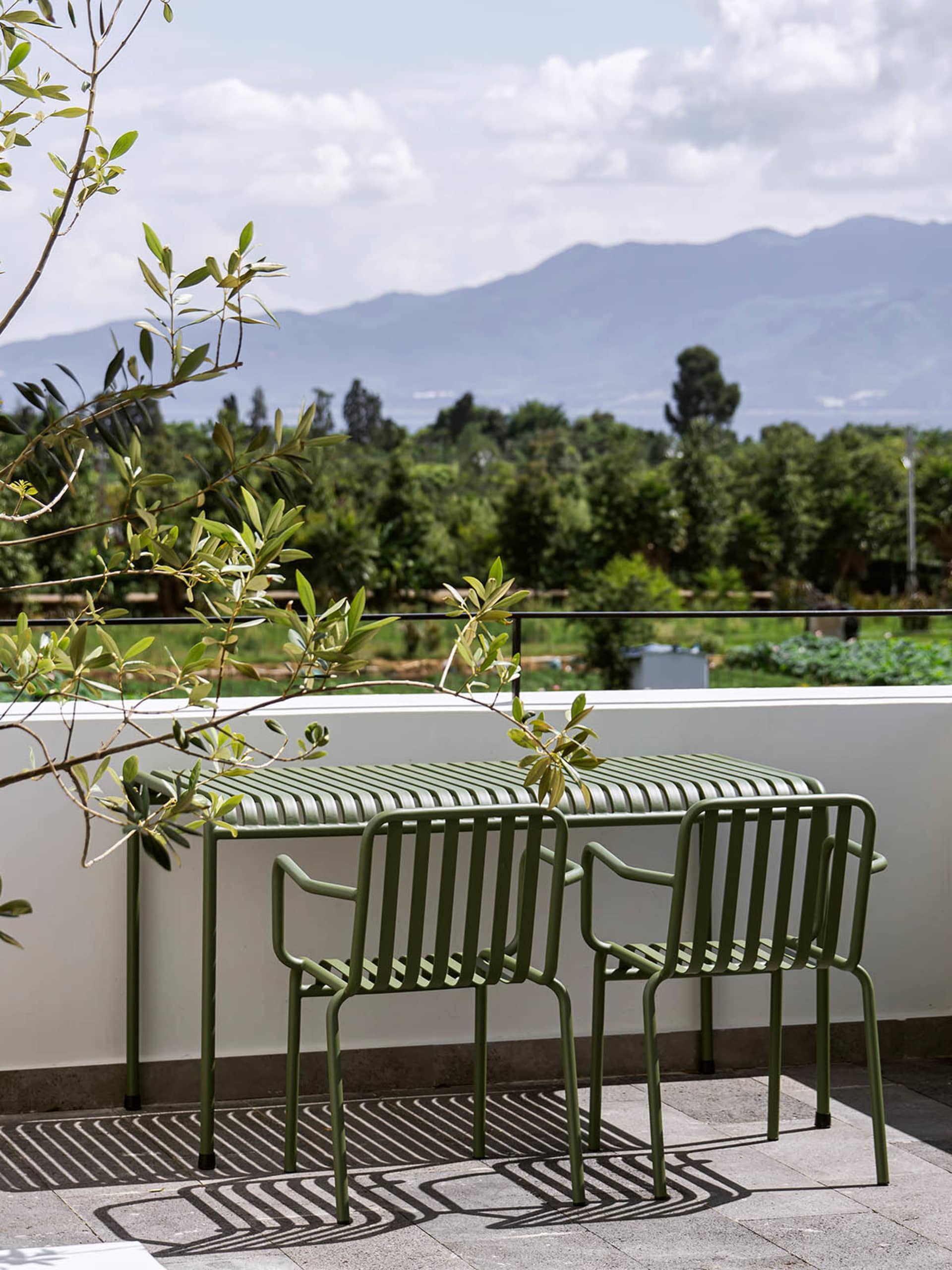 Metal outdoor furniture on a balcony overlooking a mountainous landscape.