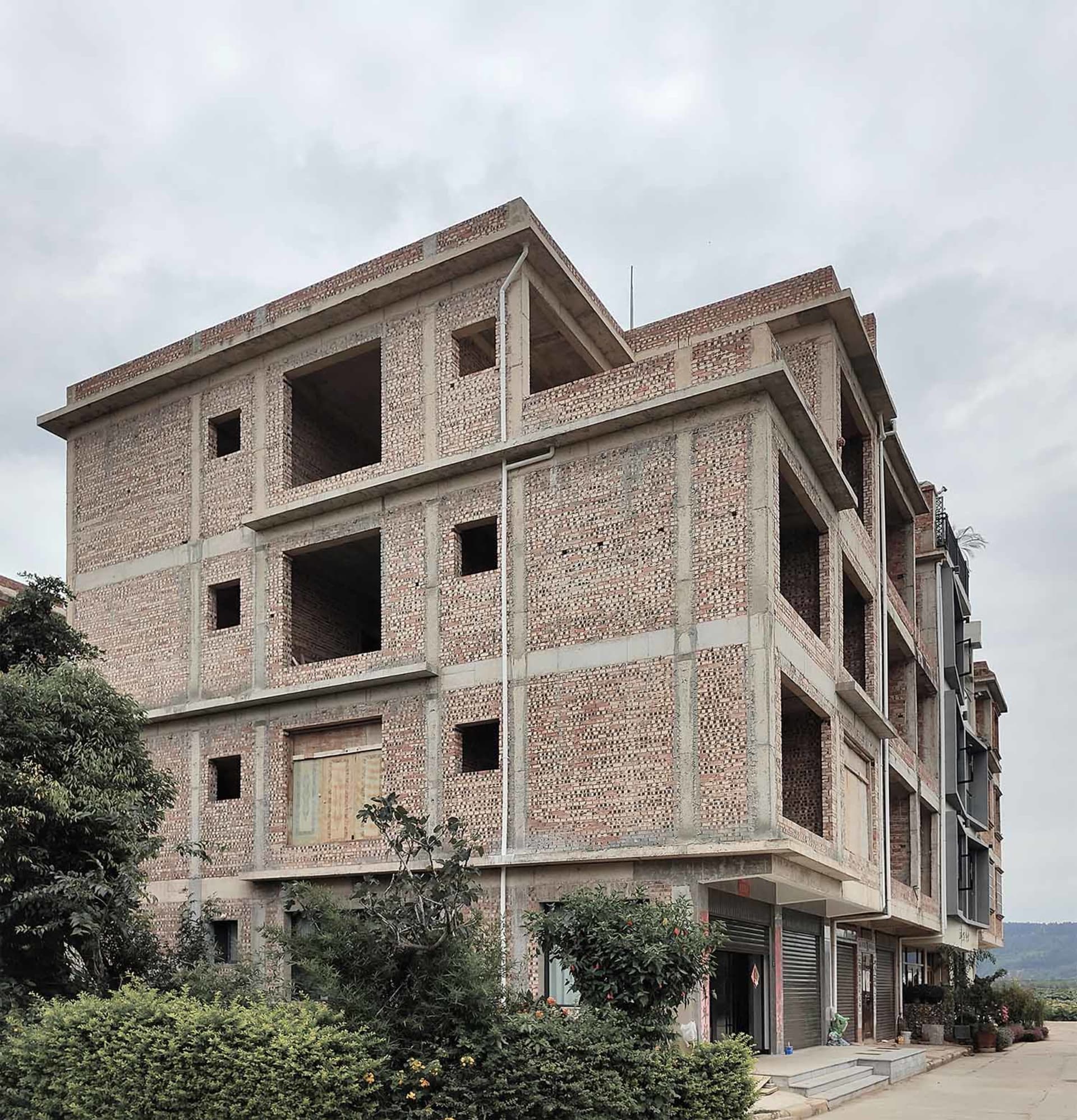 A brick building under construction with unfinished floors and open windows.