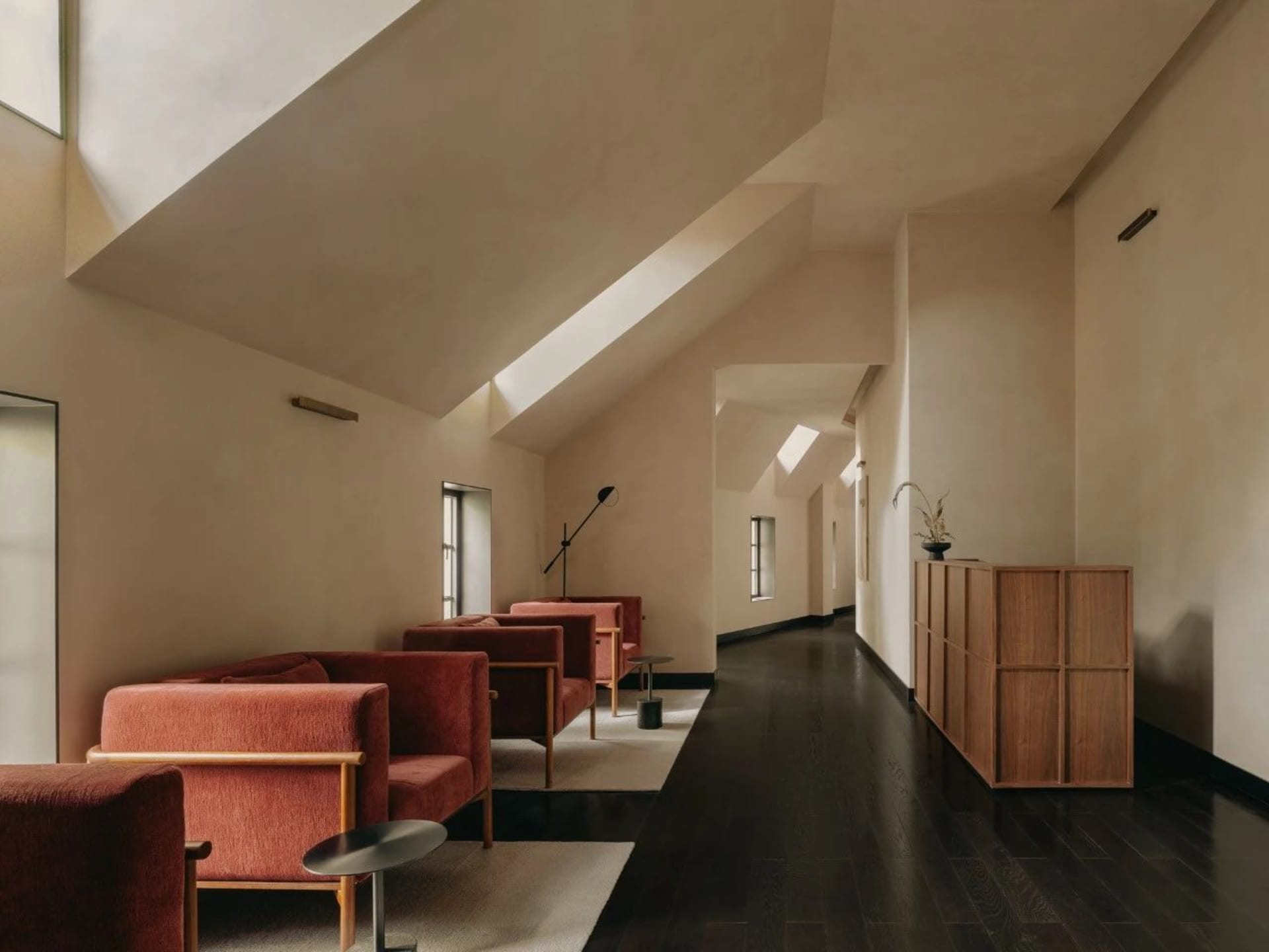 A modern living room with red upholstered furniture, dark hardwood floors, and white walls.