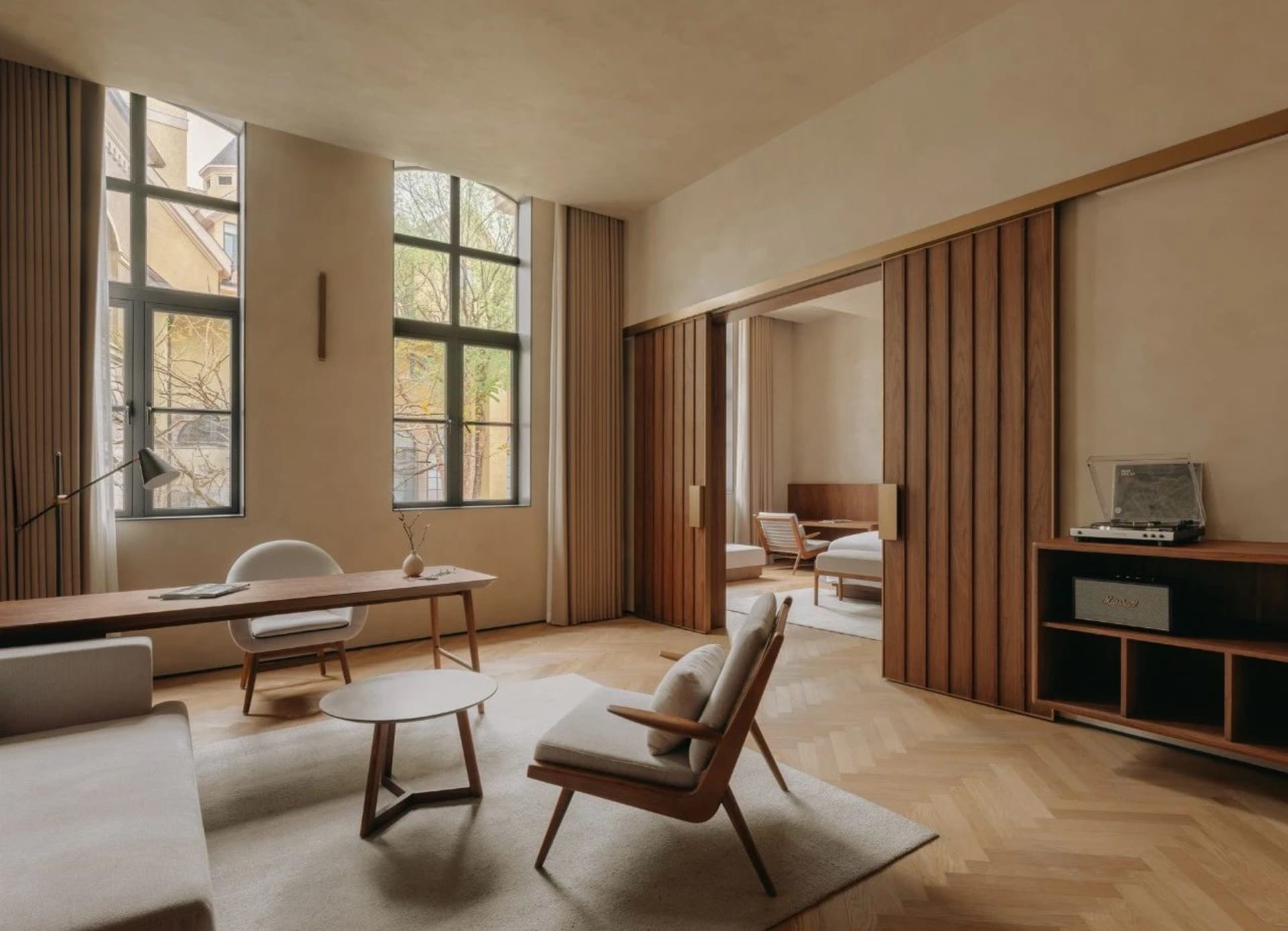 A modern living room featuring wooden paneling, a white sofa, a round coffee table, and wooden furniture.