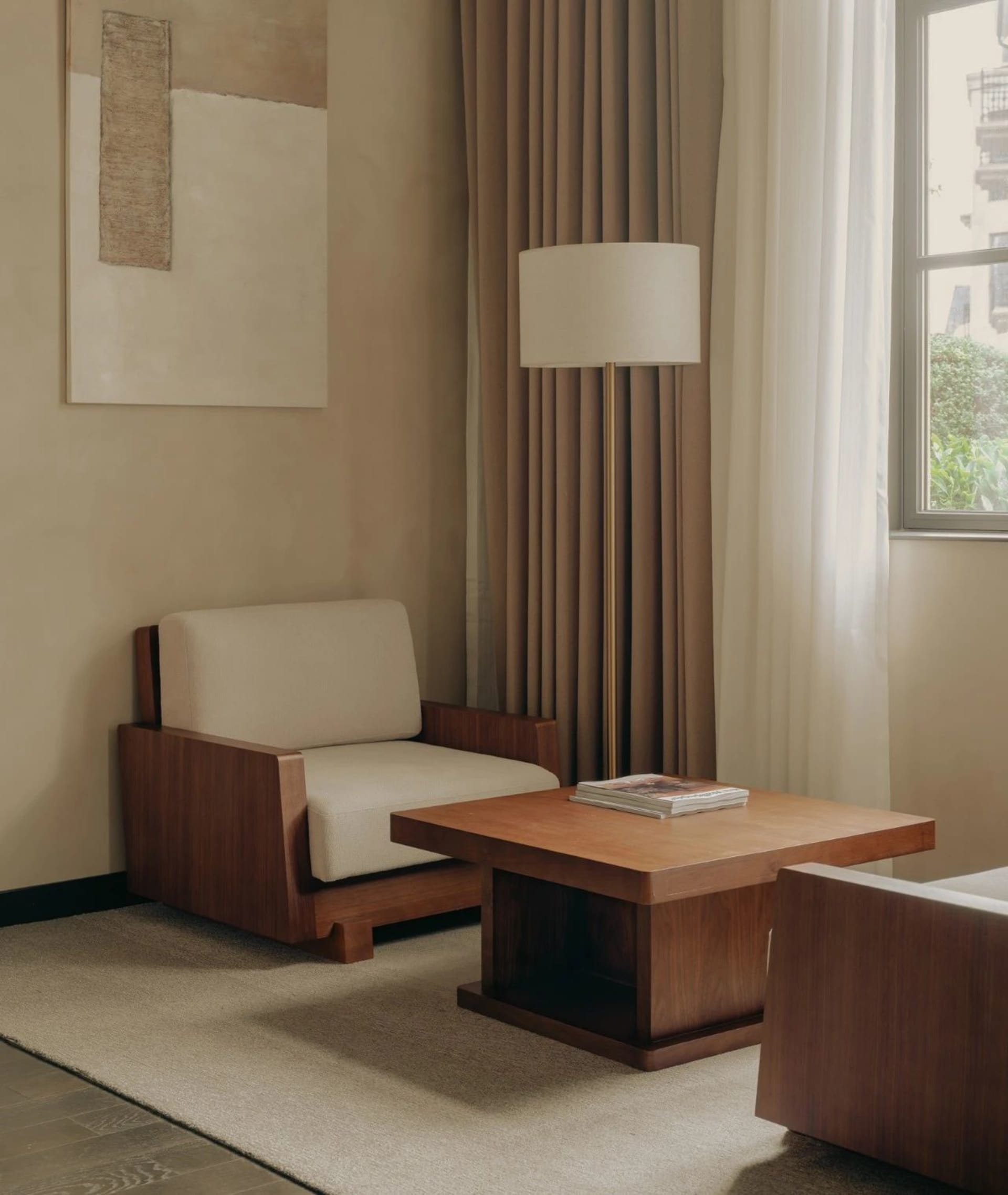 Modern interior living room featuring a wooden coffee table, beige upholstered armchair, floor lamp, and neutral color palett