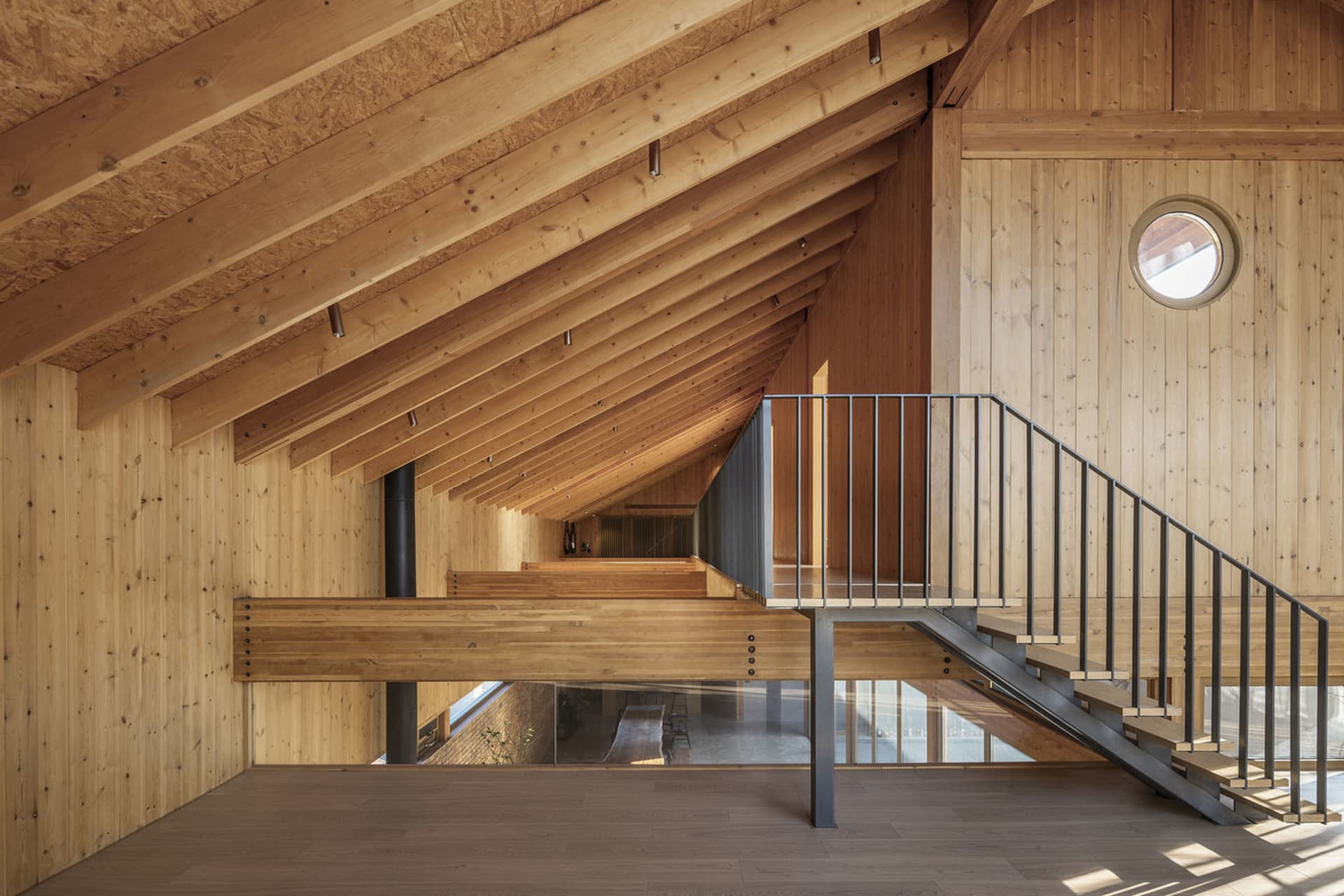 Modern loft apartment featuring wooden structural elements and a metal staircase.
