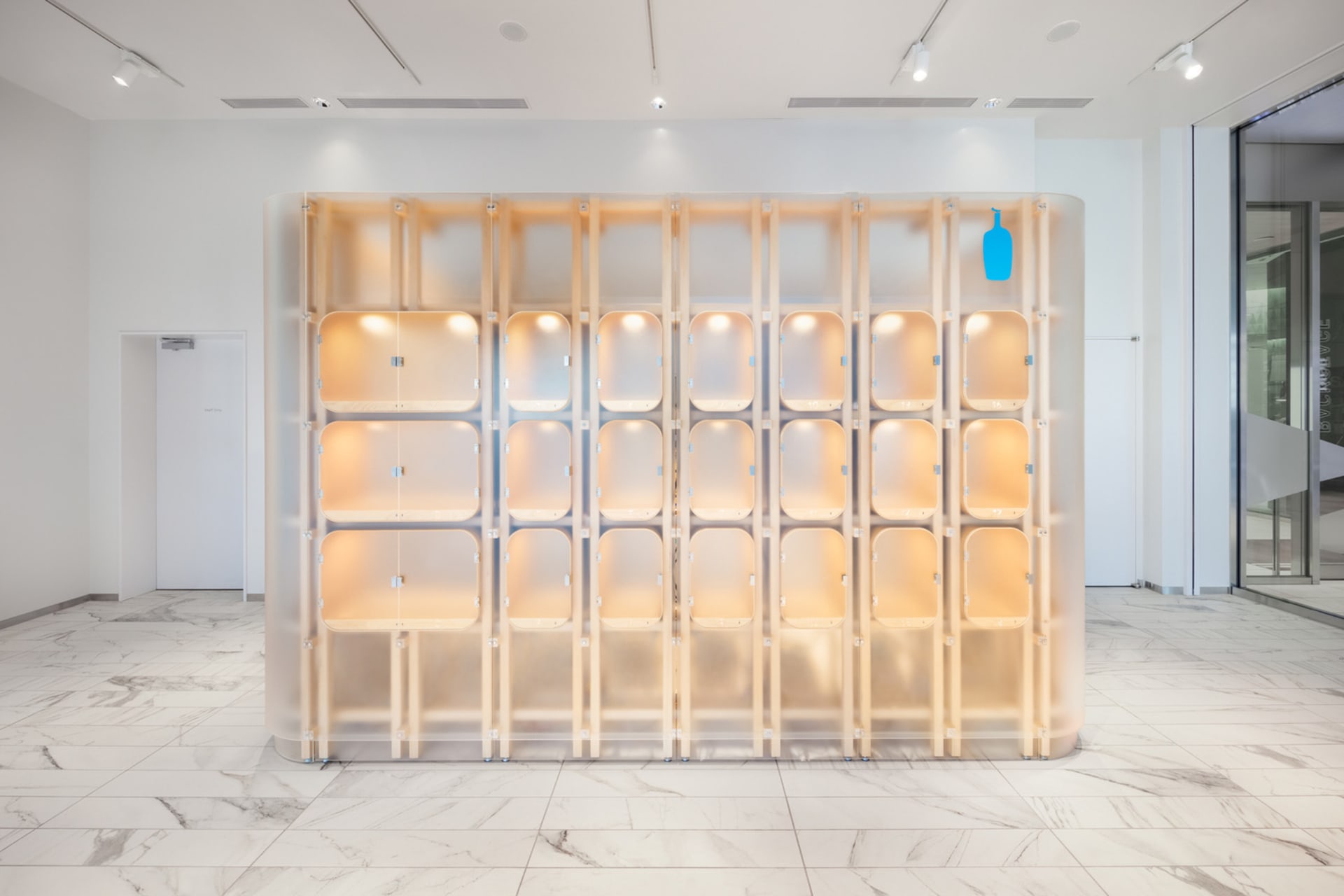A modern interior featuring a glass storage vestibule with warm lighting.