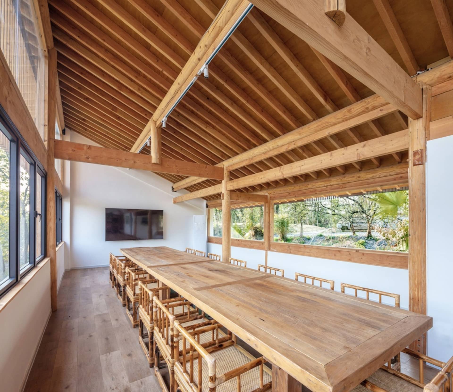 A spacious conference room with wooden tables and chairs surrounded by large windows.