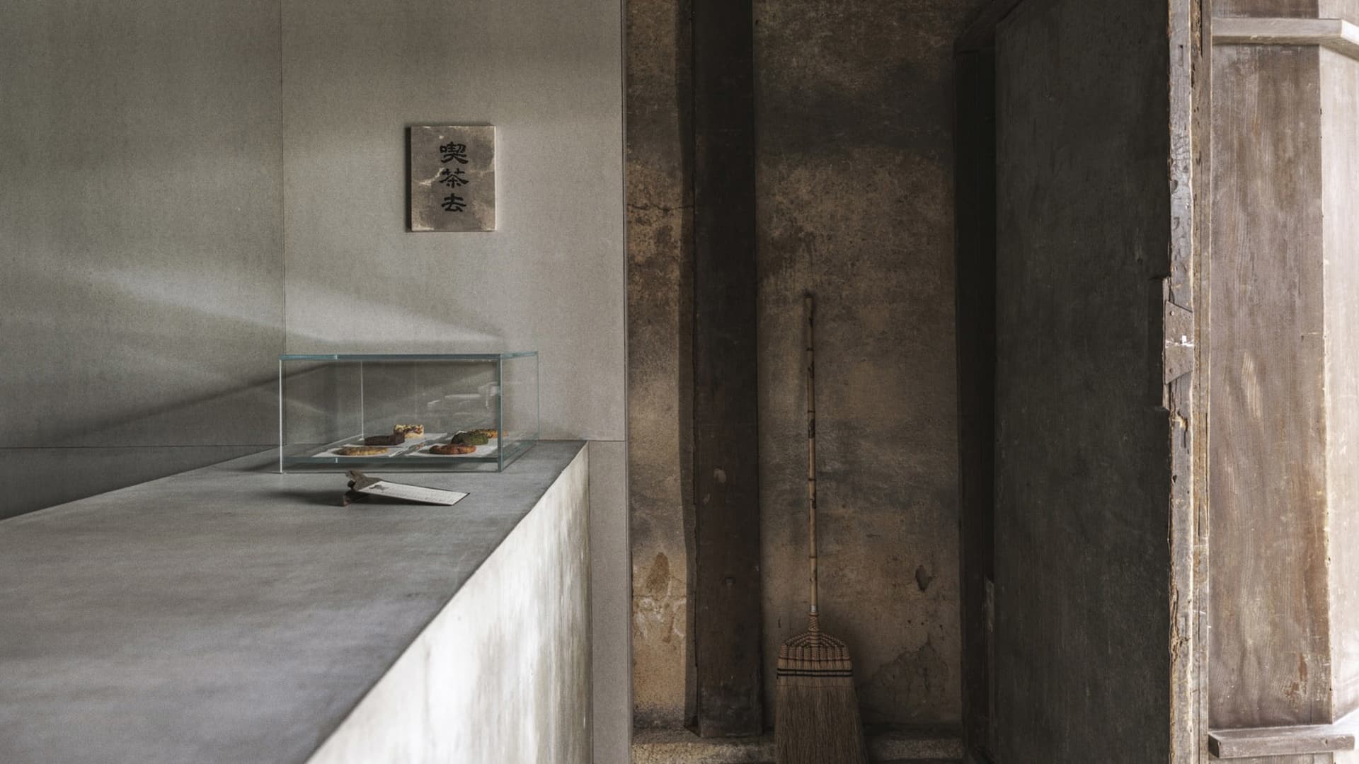 Minimalist interior design featuring a concrete wall with a glass box containing food items.