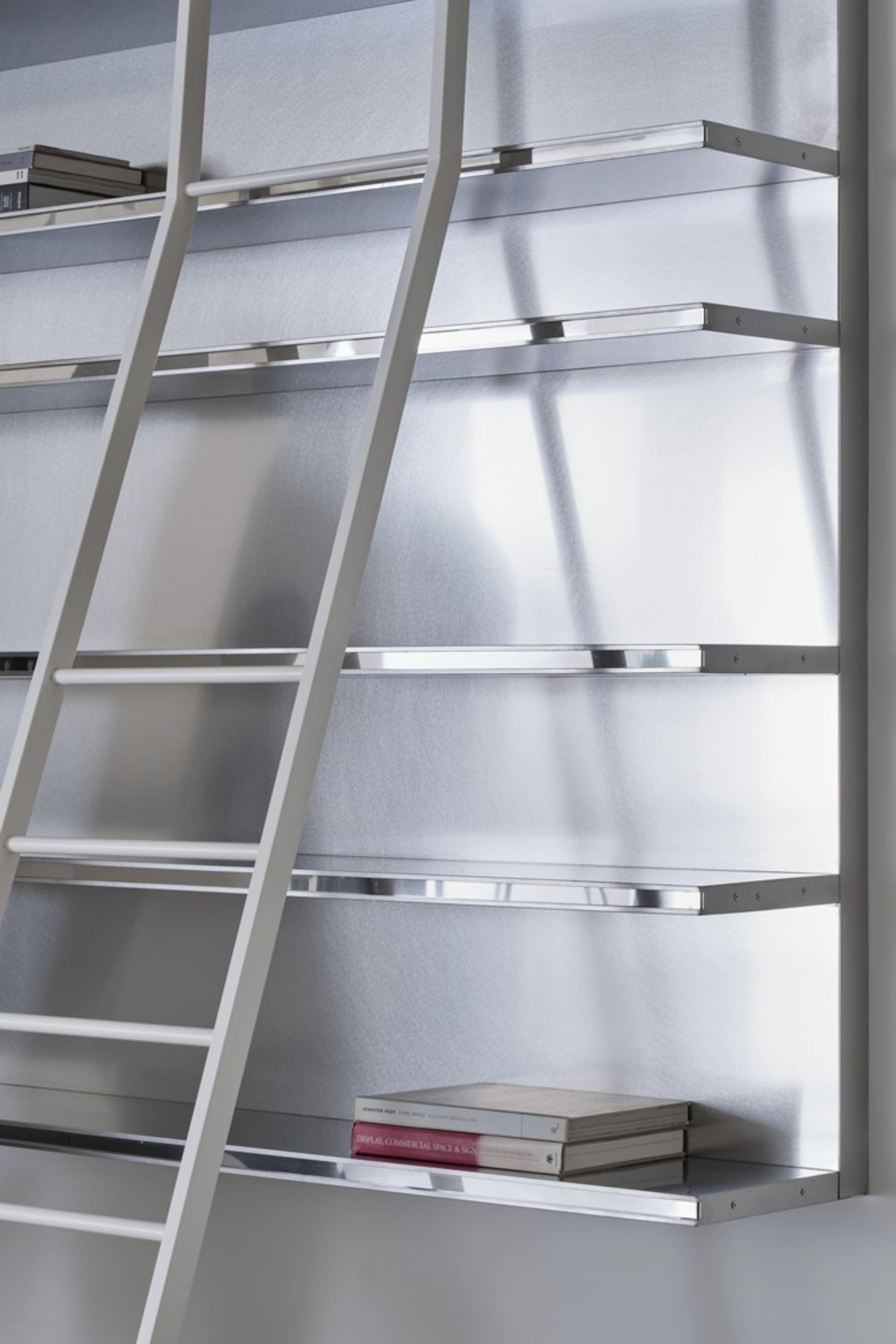 A metal shelving unit with a ladder on a white wall.