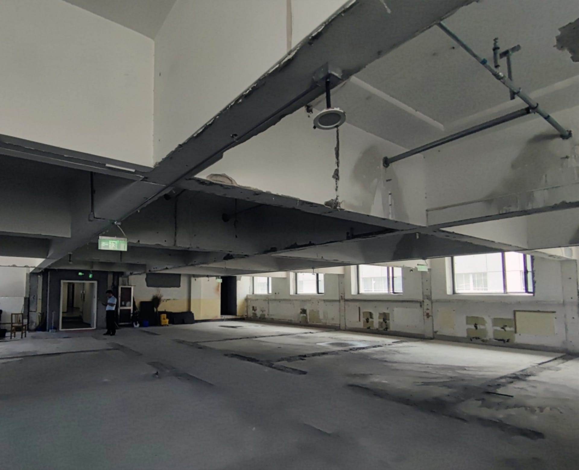 Minimalist office space with concrete walls and a high ceiling.