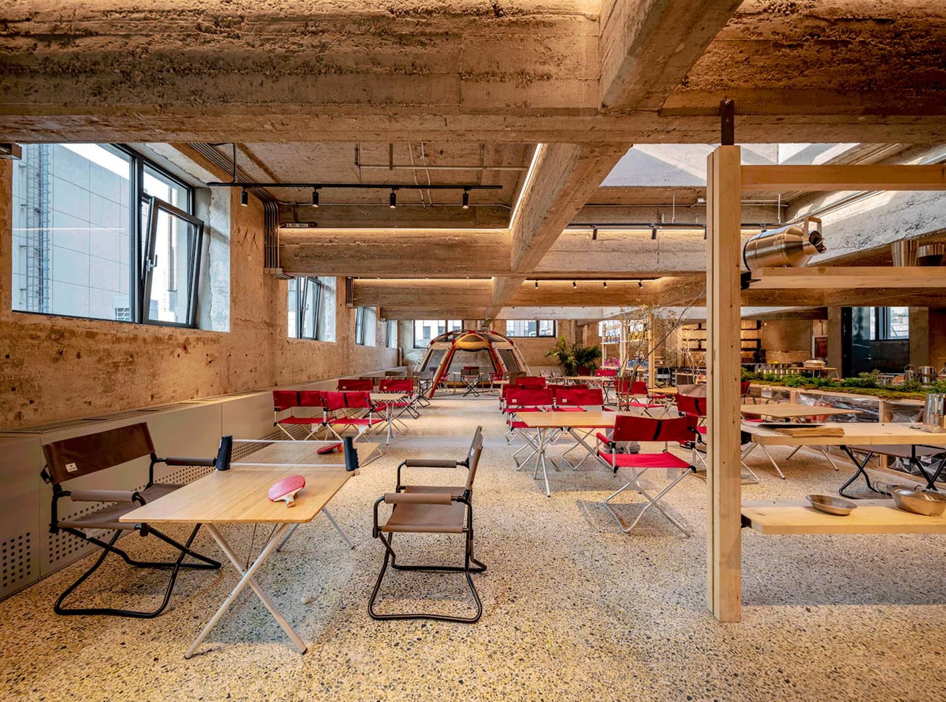 An industrial-style office-cave with concrete walls and red-cloth-covered furniture