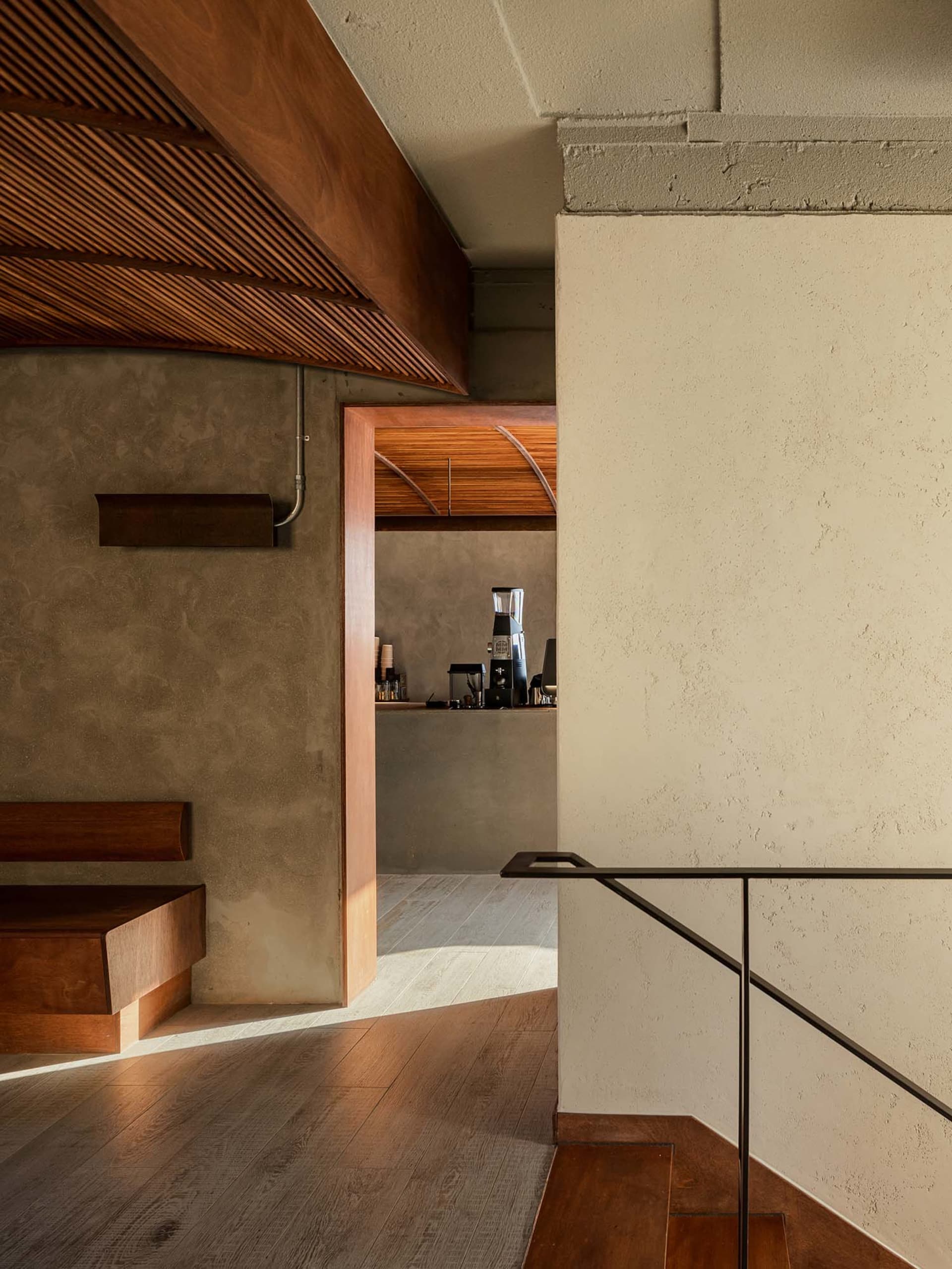 Interior of a modern coffee shop featuring a sleek bar counter made of wood and concrete with a minimalist design.