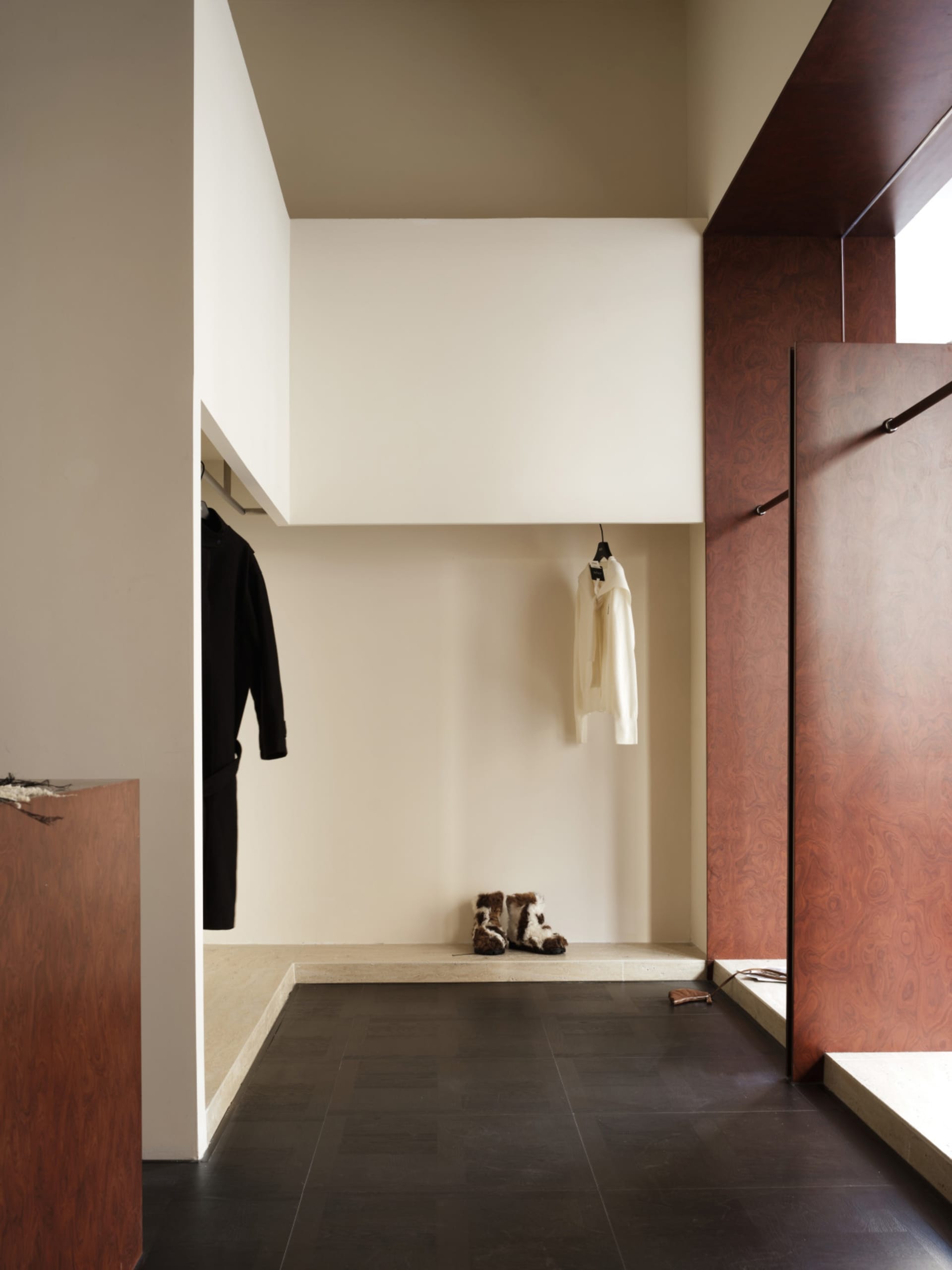 A minimalist wardrobe with wooden elements and a black floor.