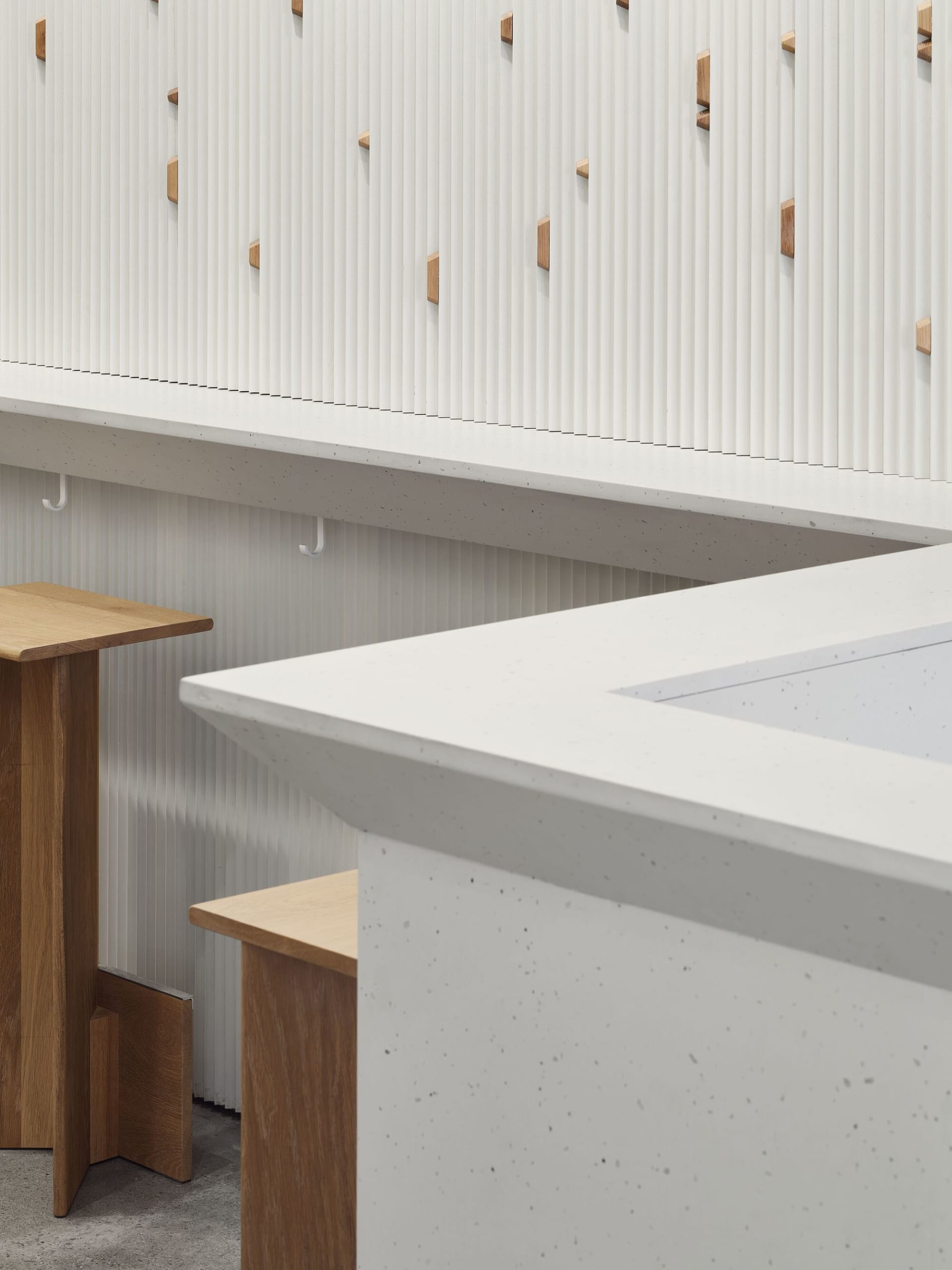 Minimalist interior design featuring a sleek, white concrete bar counter with wood accents.