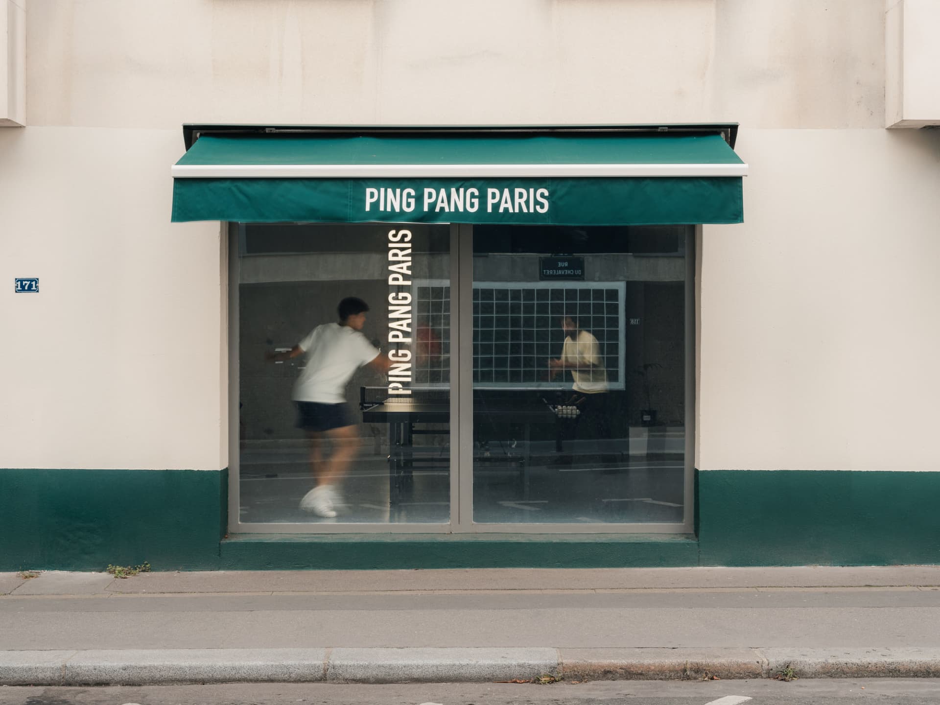 A storefront window displaying a table tennis game with people playing inside.