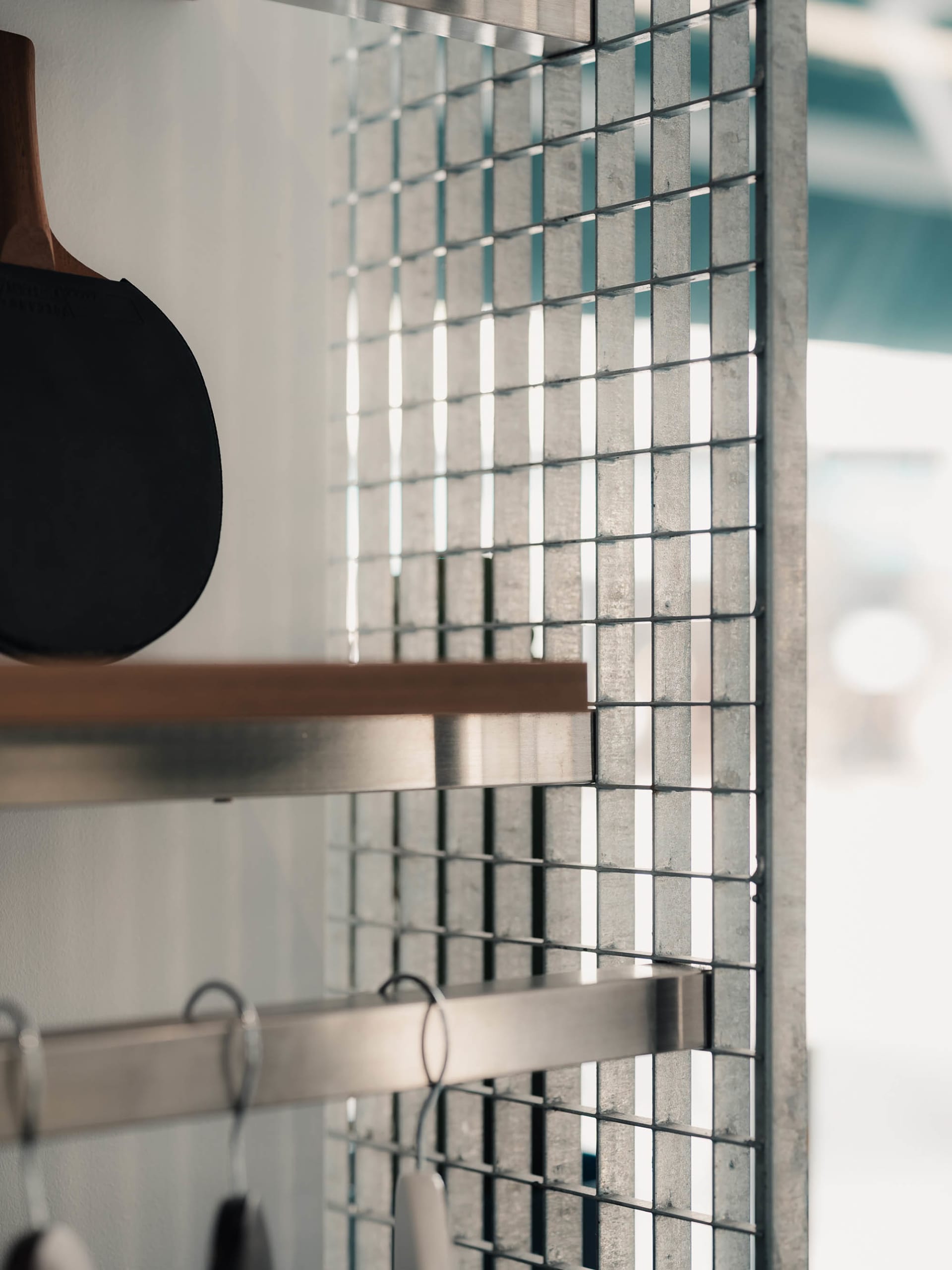 A minimalist interior design featuring a metal grid wall and wood accents.