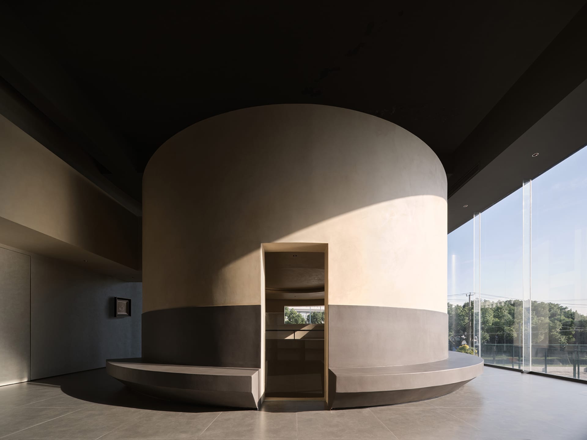 Minimalist living room with concrete walls and floor, featuring clean lines and natural light.