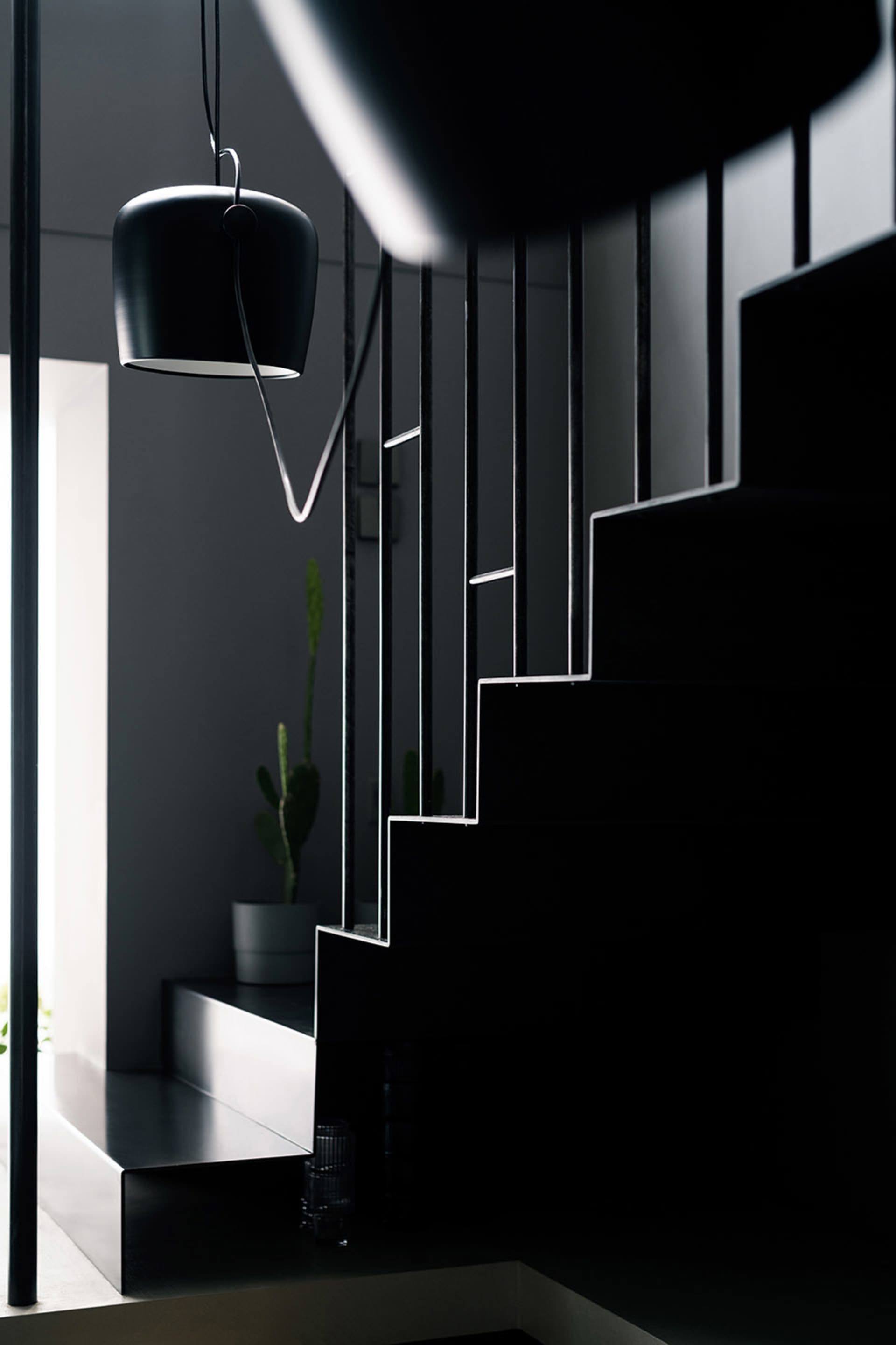 Modern minimalist interior design featuring glass stairs and black elements.