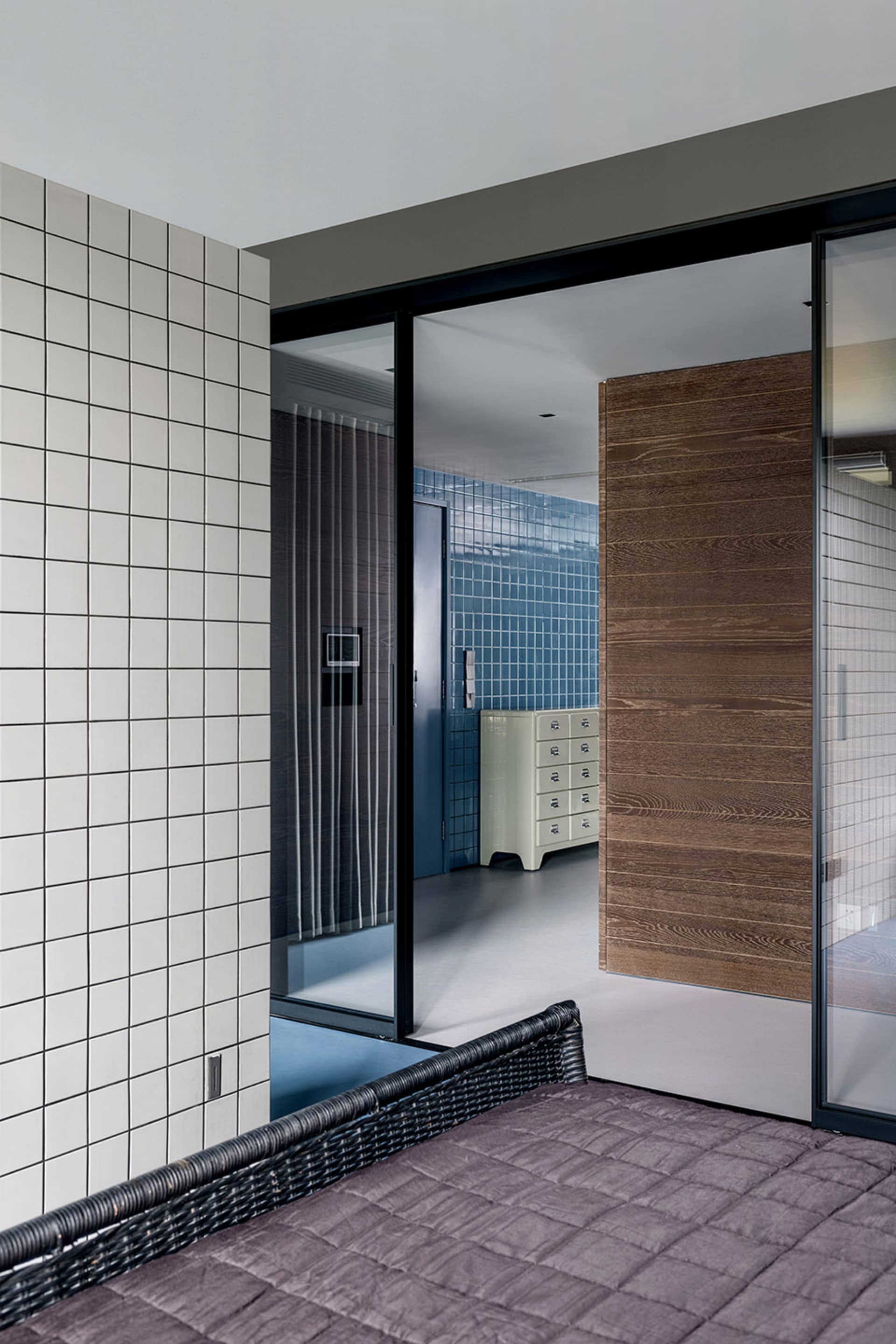 Modern bedroom featuring a wicker bed, blue tiles, and wood paneling.