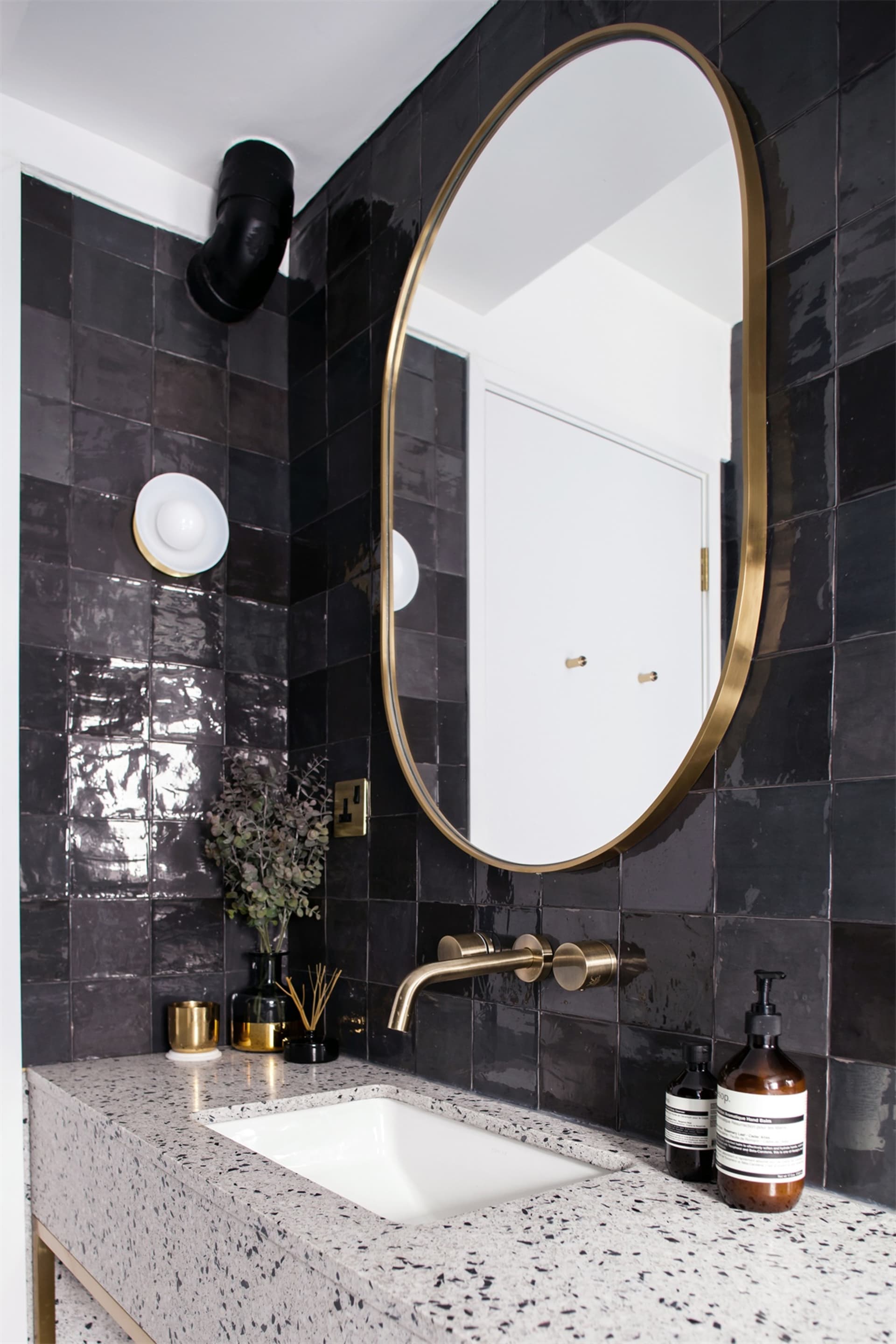 Modern black and white bathroom with a terrazzo countertop and brass fixtures.