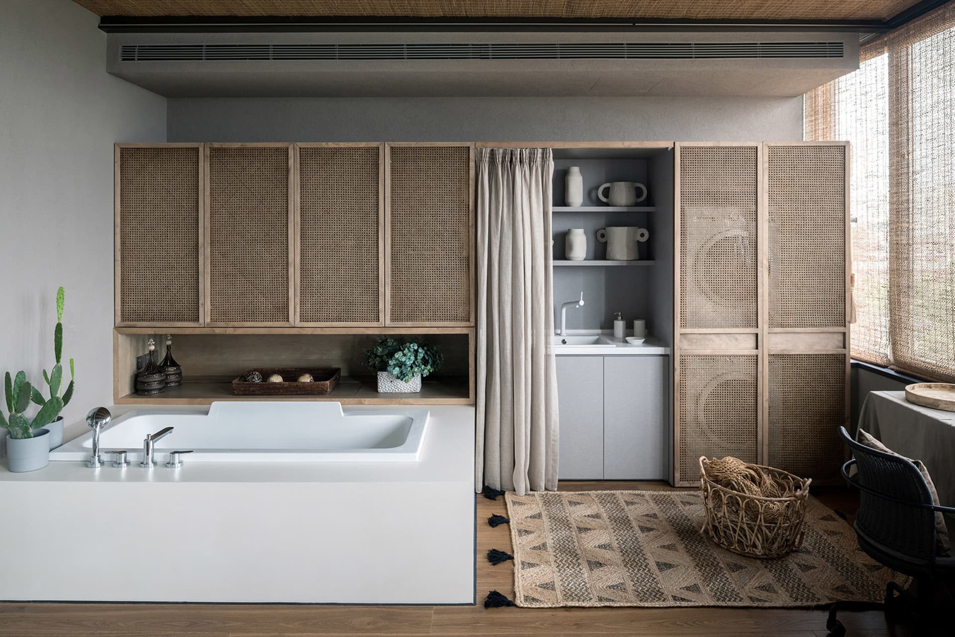 Industrial-style bathroom featuring wooden cabinets, ceramic fixtures, and a rattan rug on hardwood floors.
