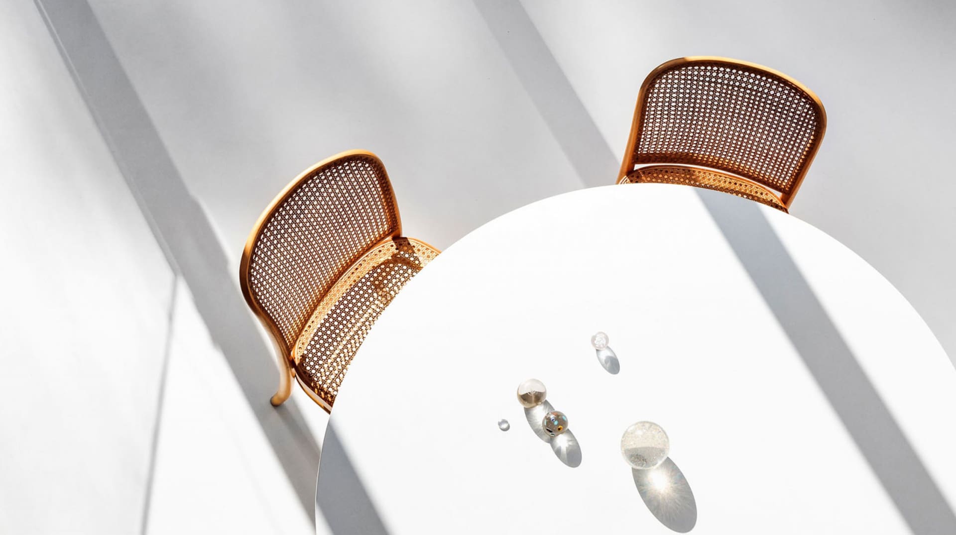 Two minimalist metal-woven fabric dining chairs with a white round table.
