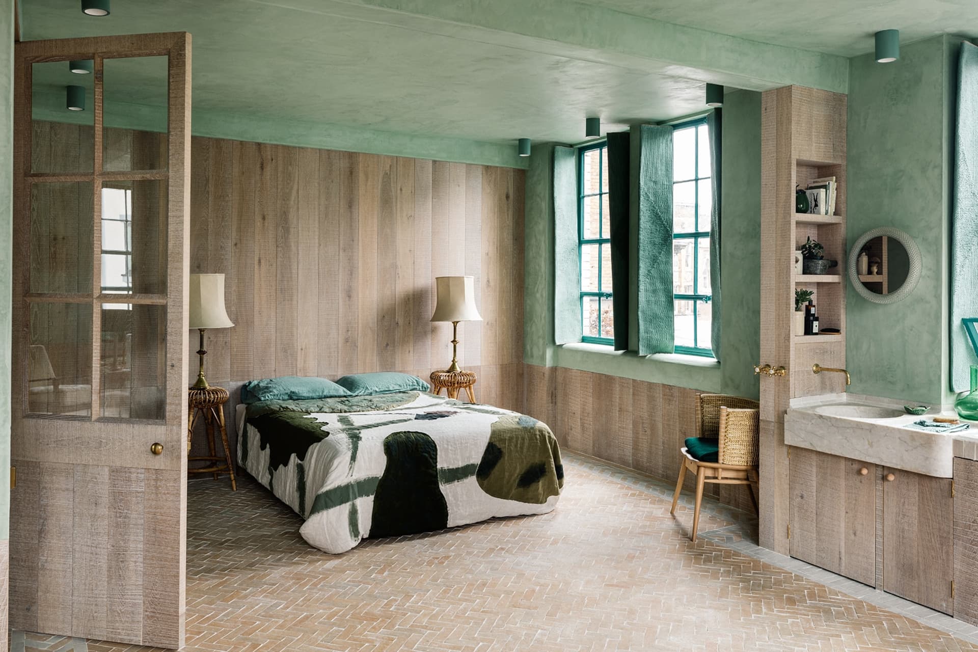 A modern bedroom with green sheeting, wood paneling, and a stone sink.