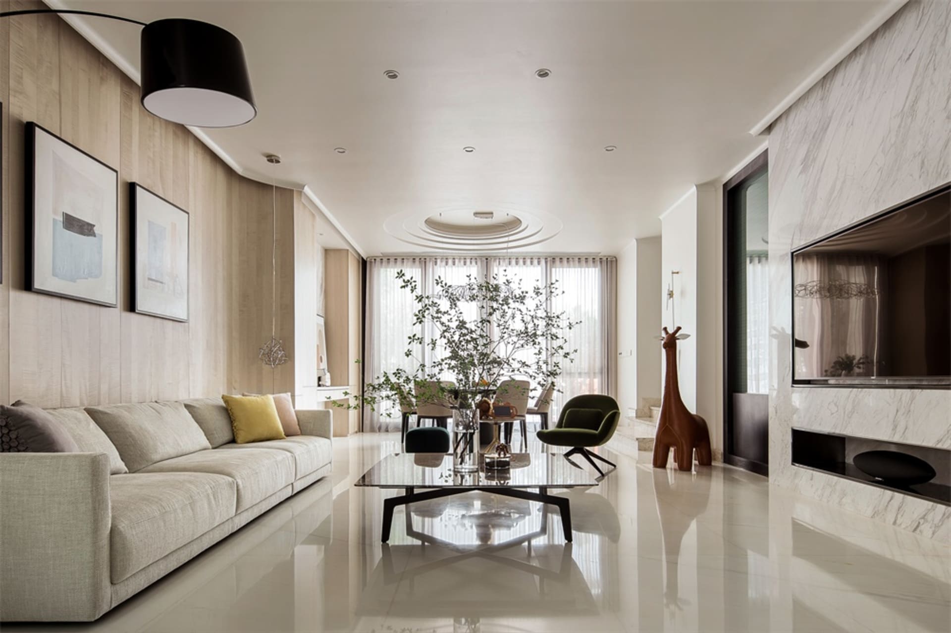 A modern living room featuring marble flooring, a large beige sofa, and a contemporary coffee table with greenery.
