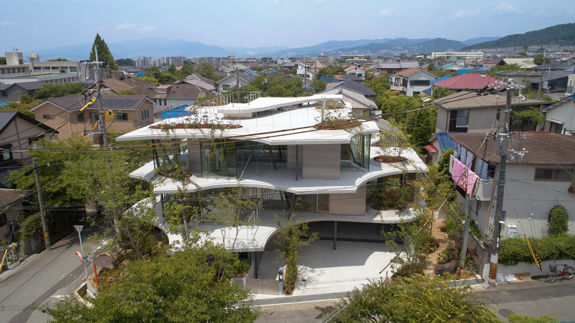 A modern, multi-level residential building with glass walls and a concrete exterior.