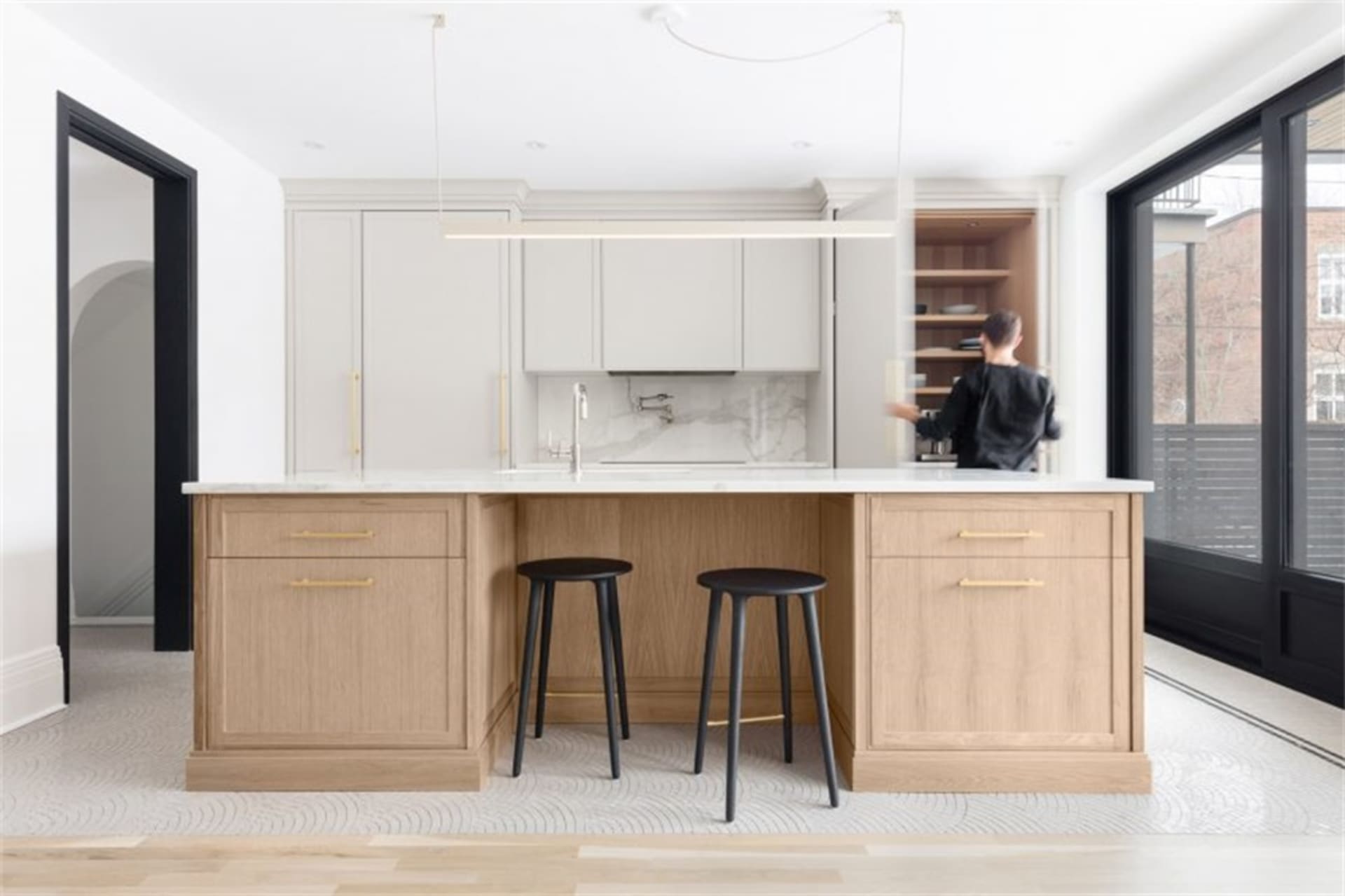 A modern residential kitchen featuring light wood cabinets and marble countertops.
