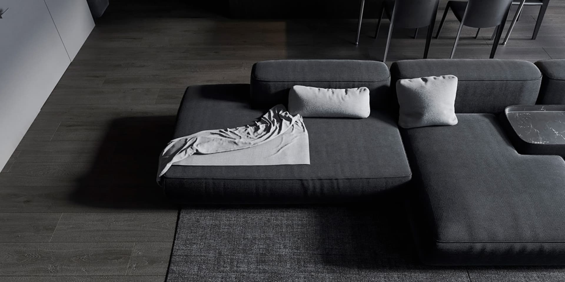 A modern living room featuring a grey fabric sectional couch with a blanket and pillows.