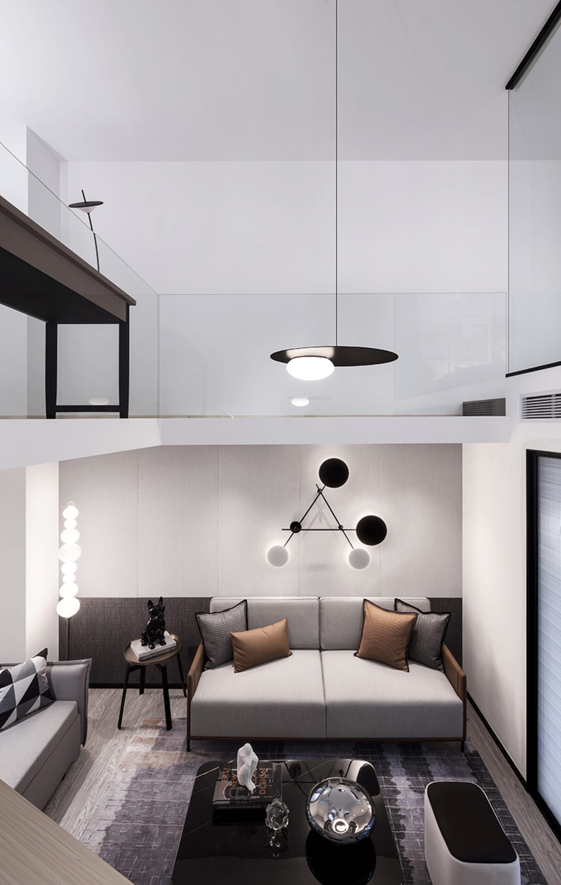 A modern minimalist living room with a gray sofa, black and white geometric light fixture, and sleek black coffee table.