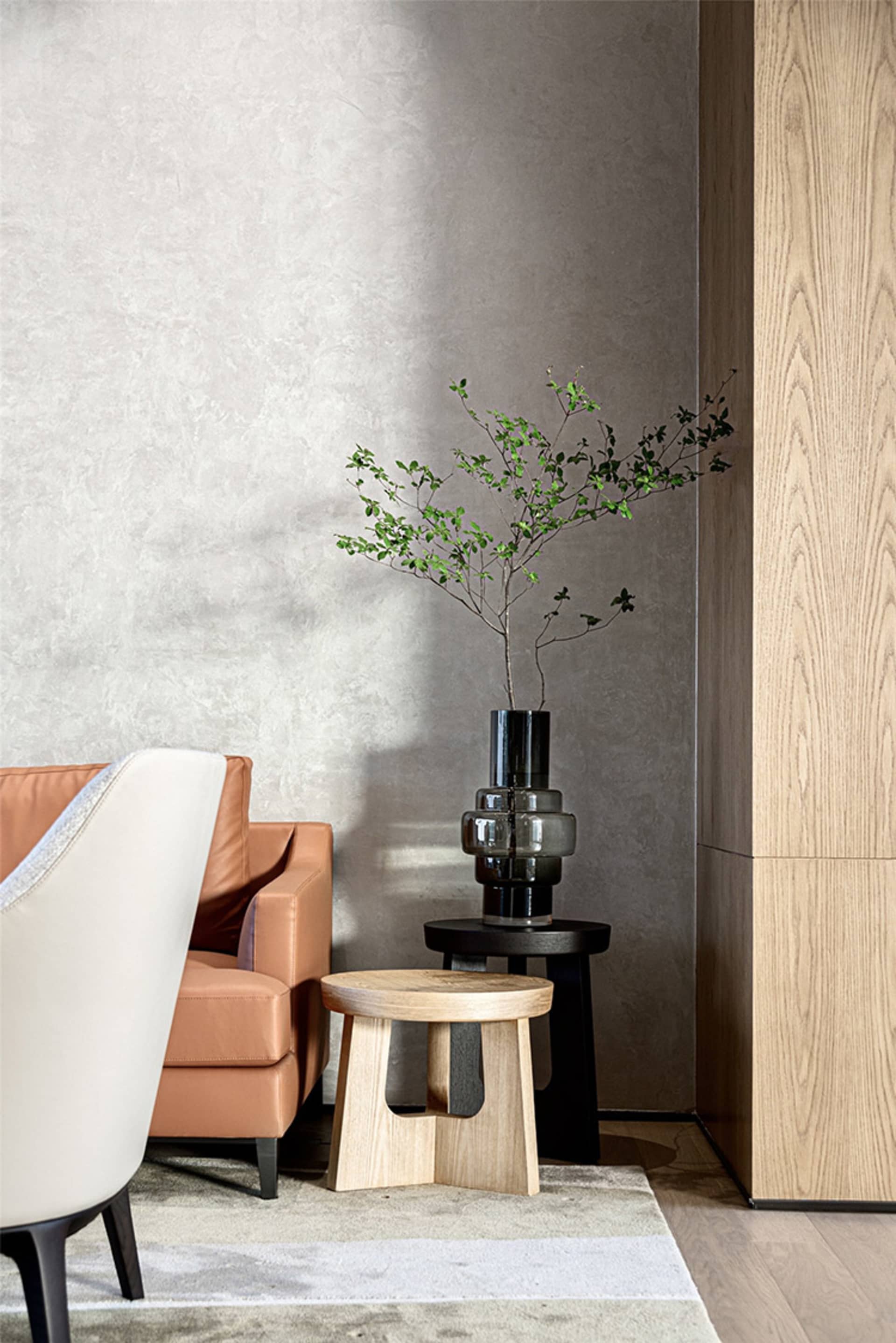 Minimalist living room featuring wooden furniture and a plant in a vase on a small wooden stool.