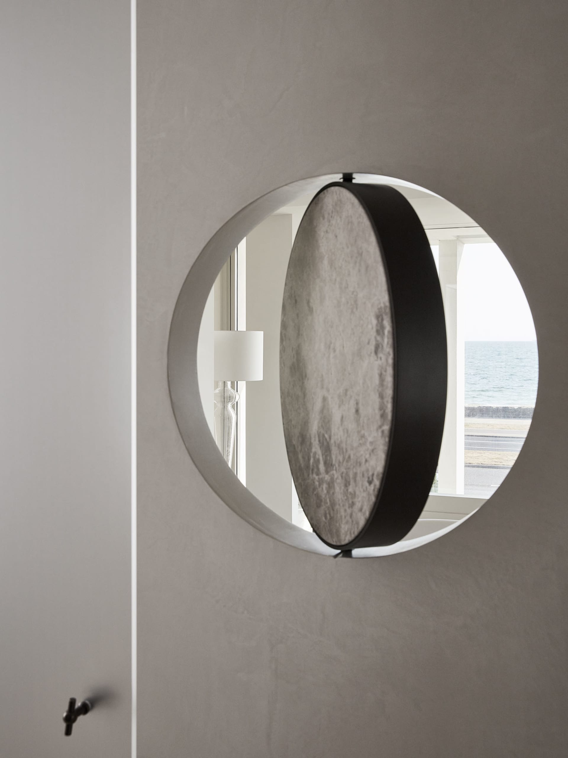 A modern decorative mirror with a metallic circular arc design mounted on a wall.