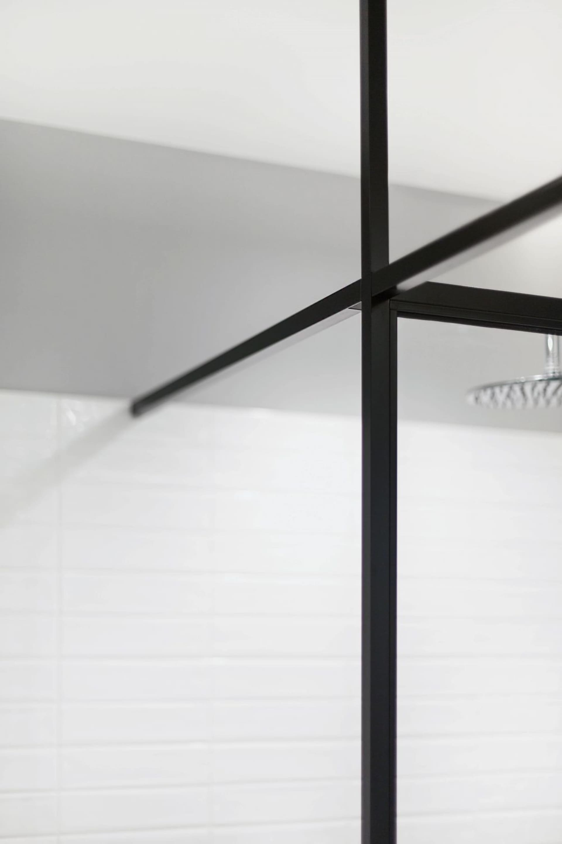 Modern minimalist bathroom featuring black metal frame, black glass shower enclosure, and white tiles.