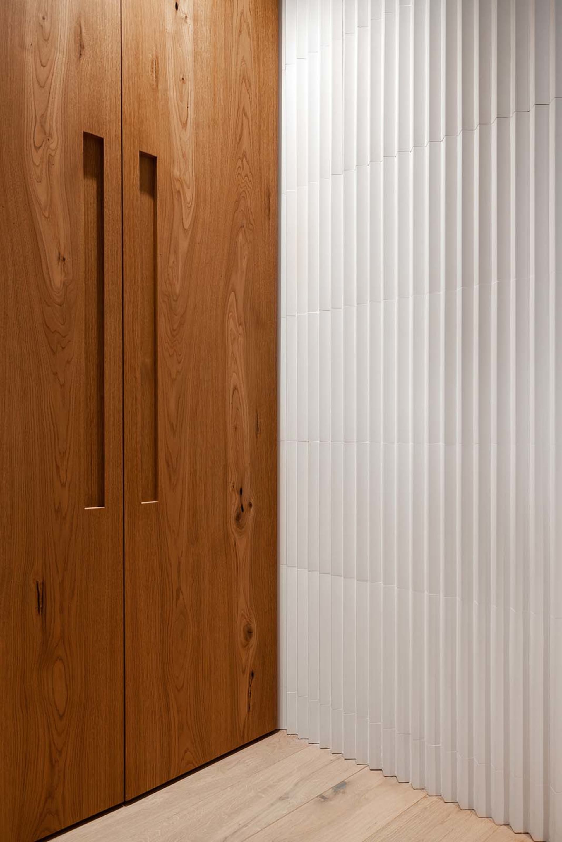 Modern wooden cabinets with vertical grain texture and light hardwood flooring.