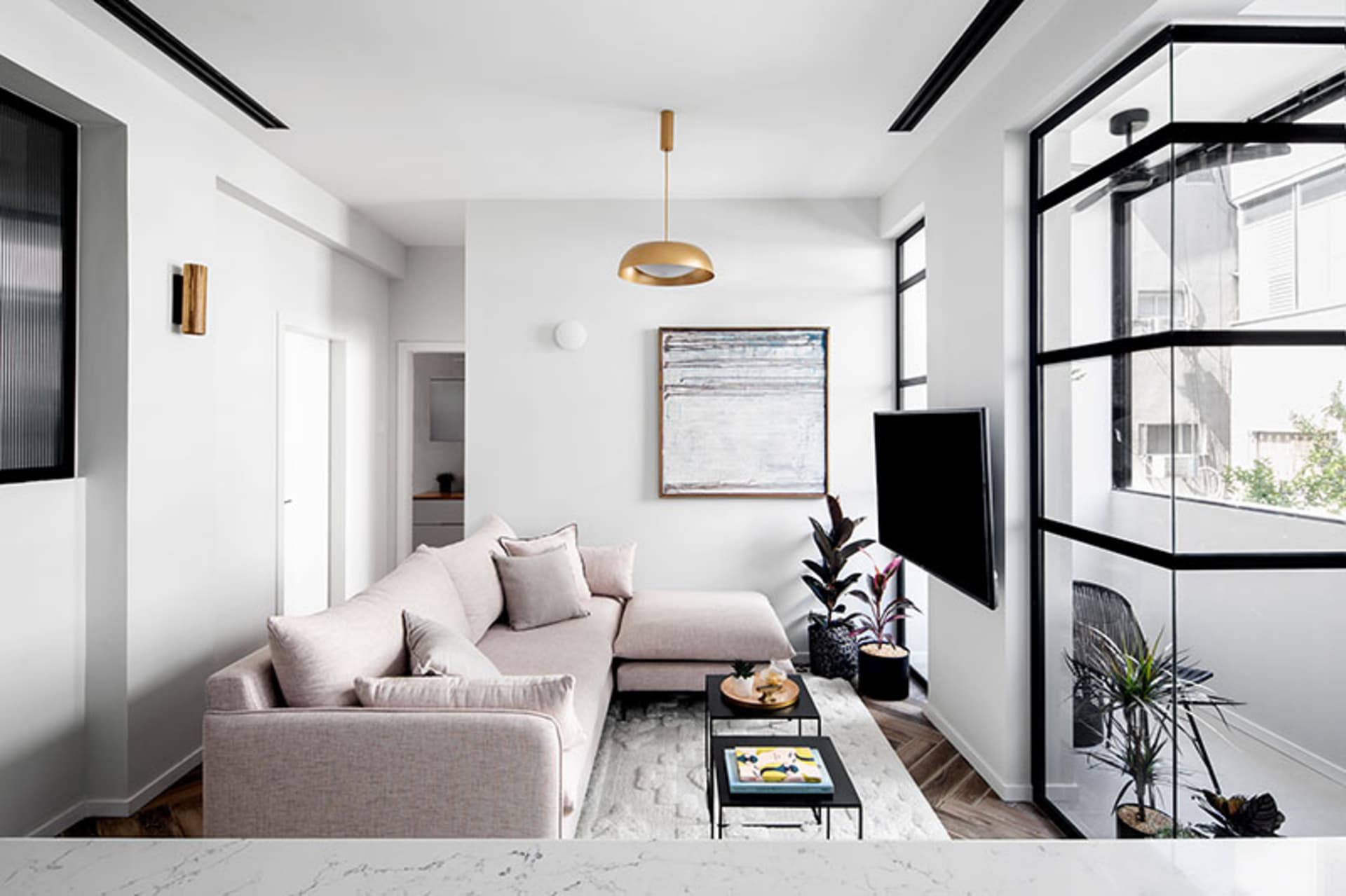 Modern living room with minimalist decor, neutral tones, and sleek white pendant light fixture.