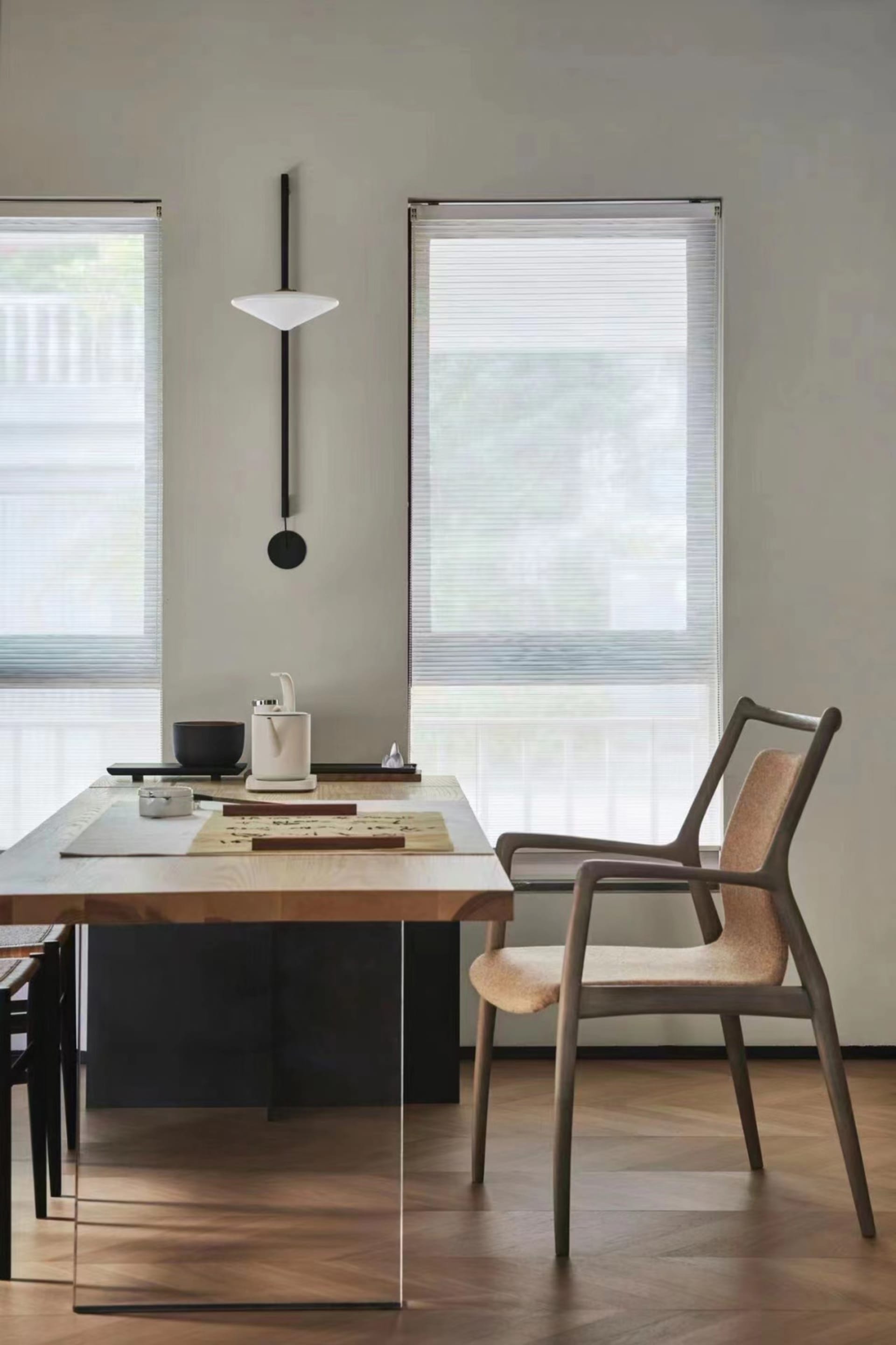 A modern home office with wooden furniture, a minimalist desk, and a hanging light fixture.